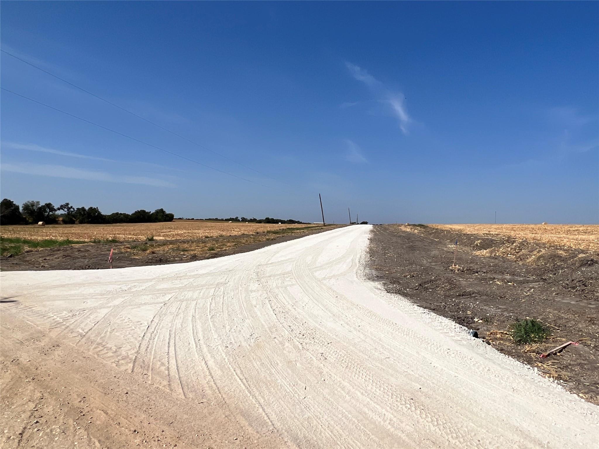 An inviting gravel road leads into a vast, sun-dr