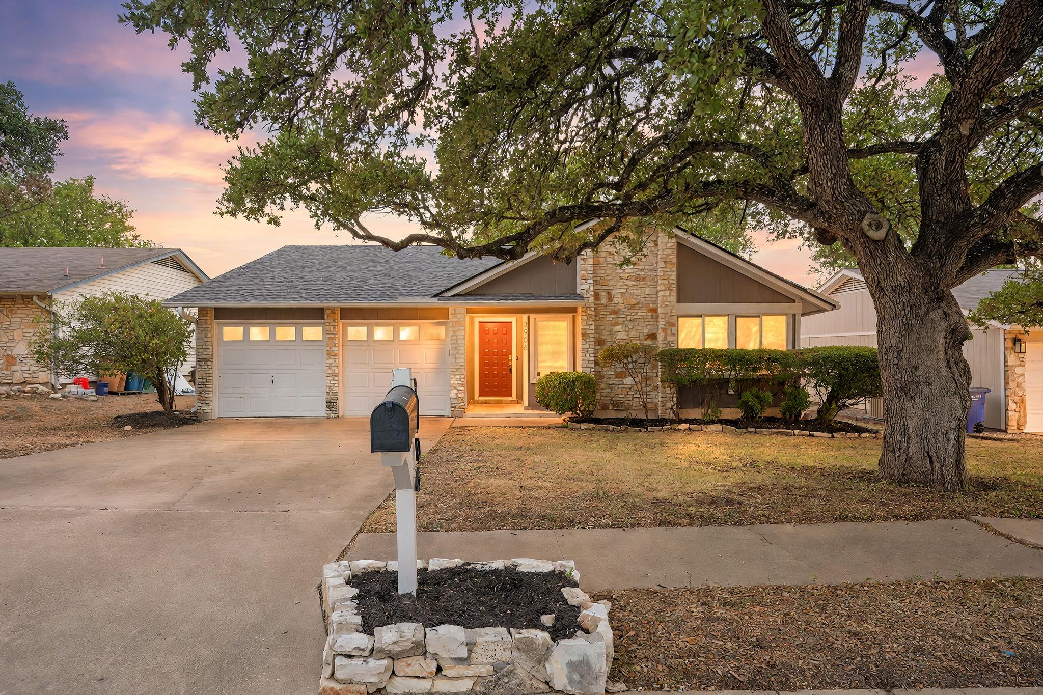 Mature oak trees frame a stone-accented exterior 