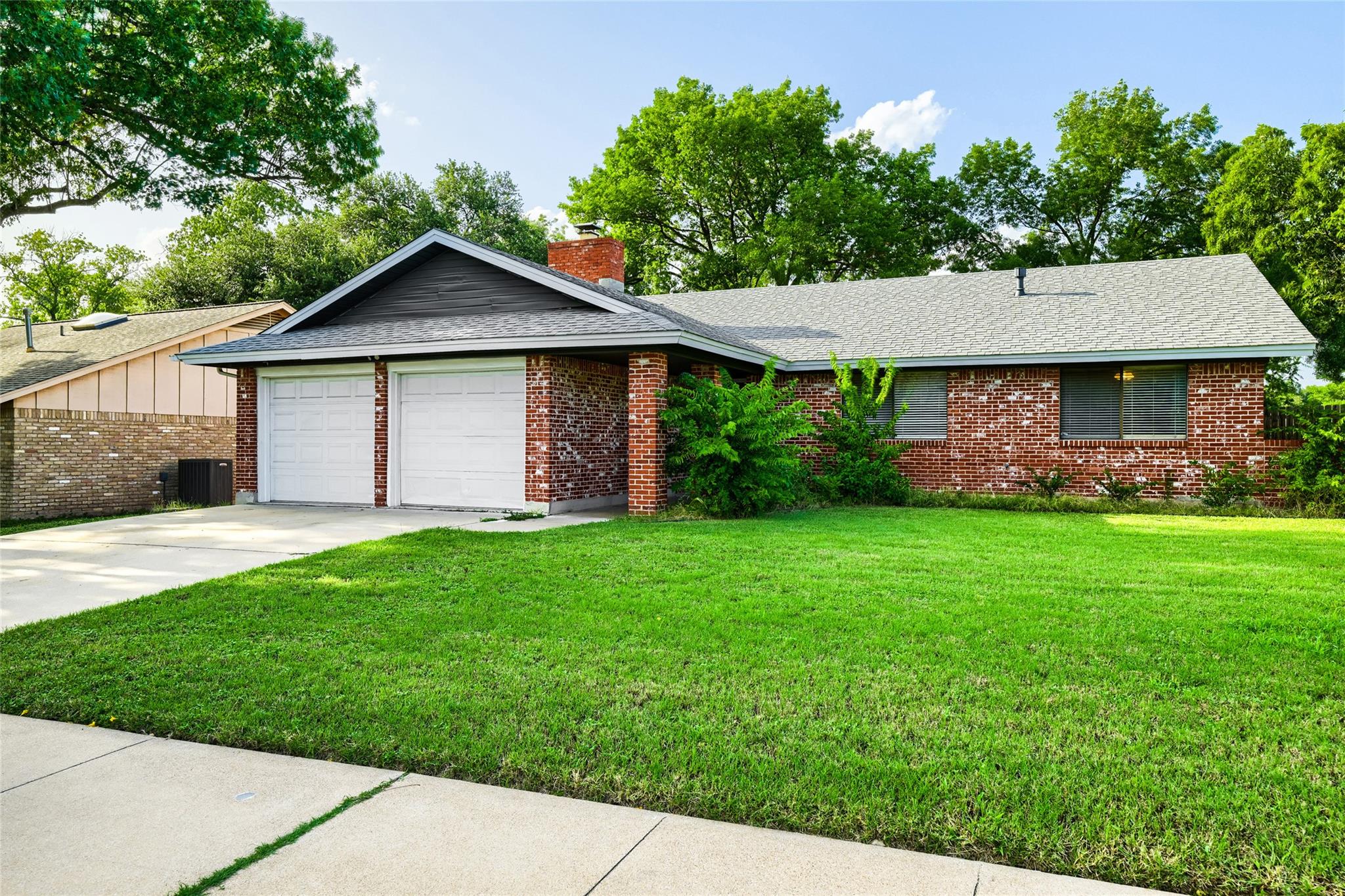A well-maintained brick exterior with a lush gree