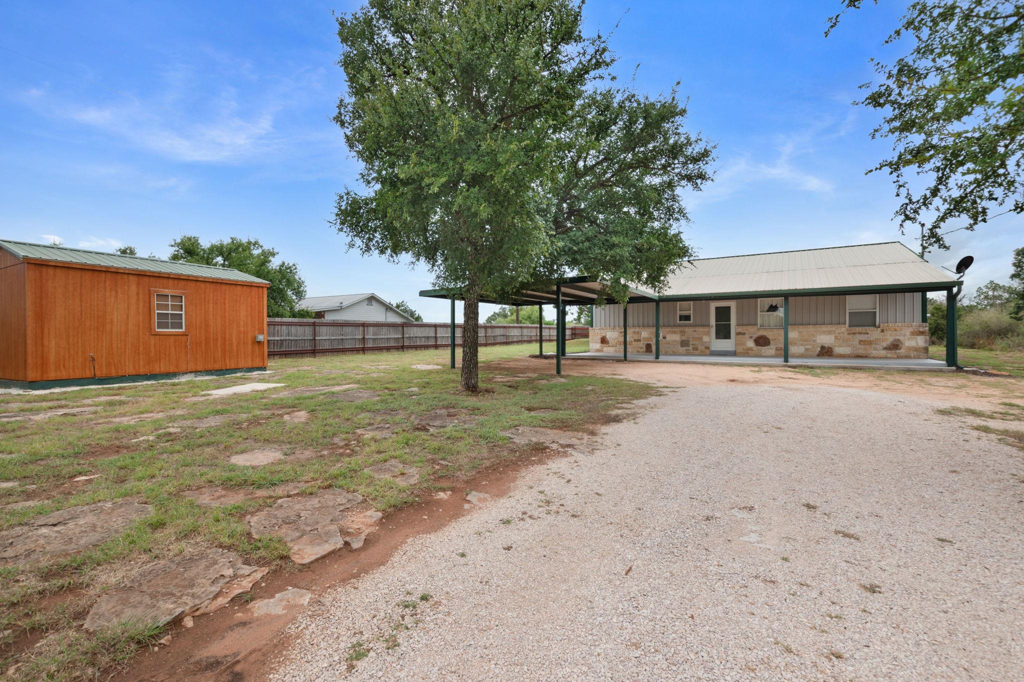 A spacious gravel driveway leads to a stone and s