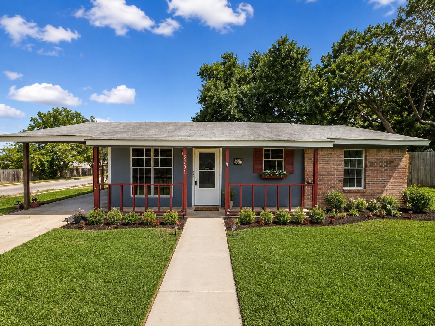 A welcoming facade features a carport, brick acce