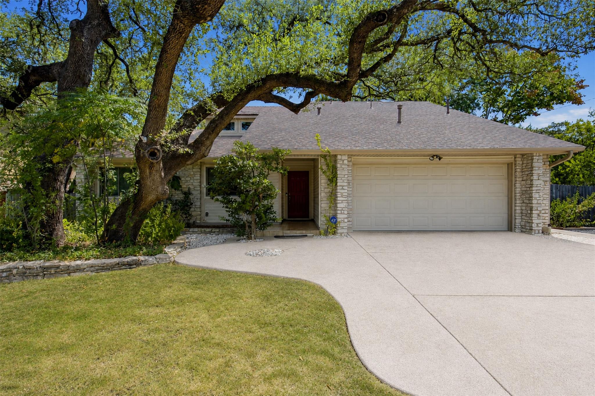Mature shade trees frame a classic stone facade a