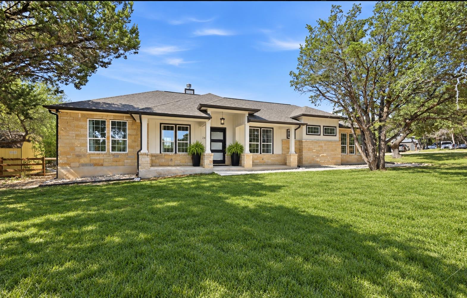 Mature trees shade a welcoming covered porch on t