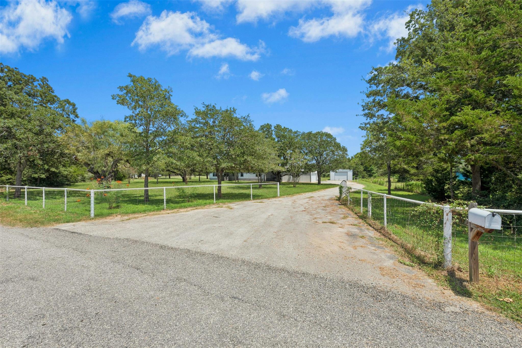 A long, graveled driveway leads to a private resi