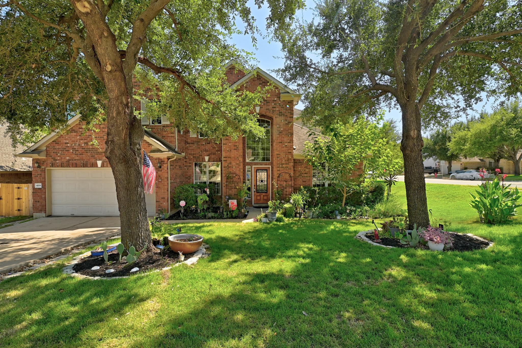 Mature shade trees frame a classic brick facade o