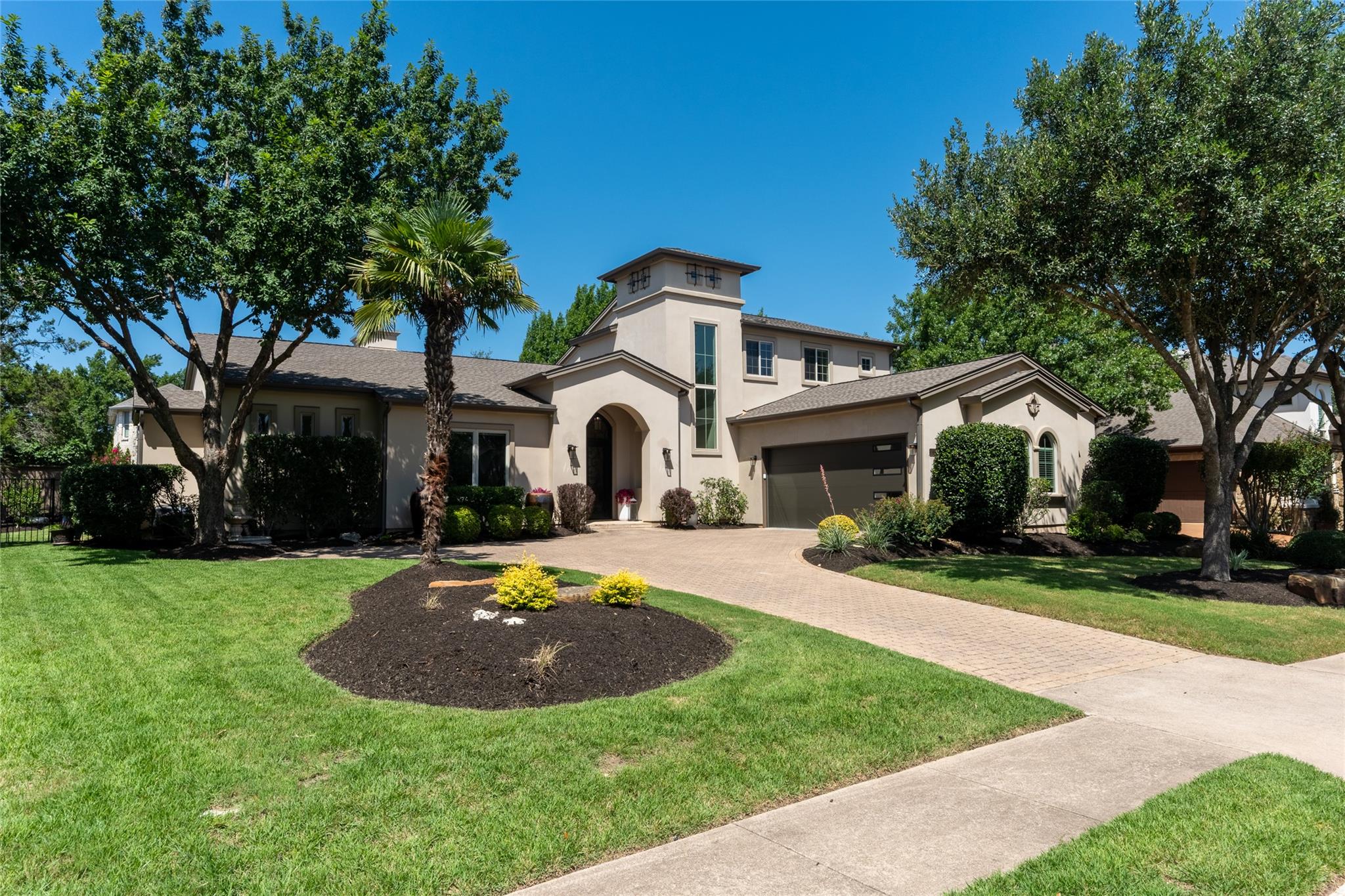 An inviting paver driveway leads to a stucco resi