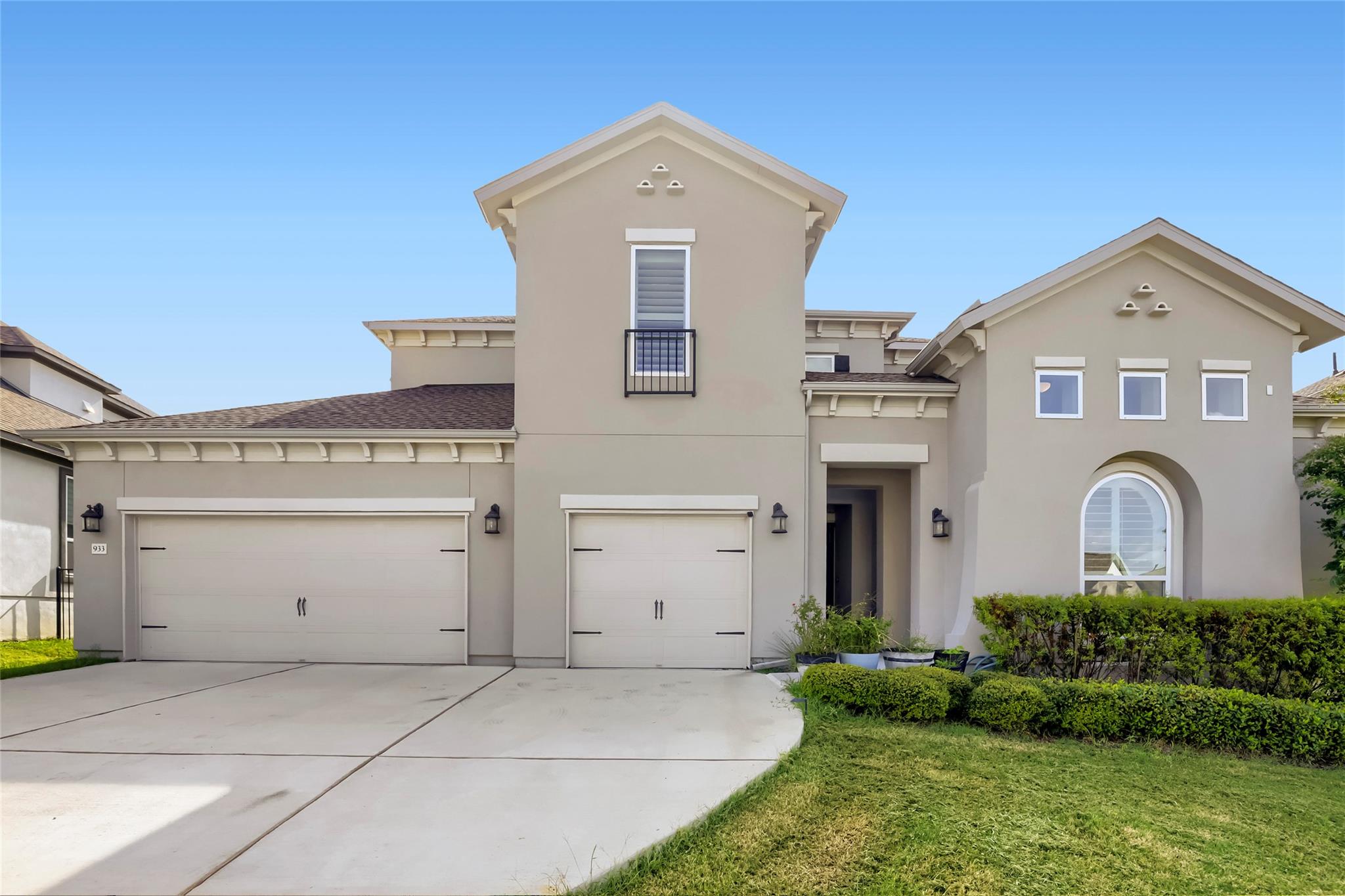 A graceful facade features twin garage doors, a p