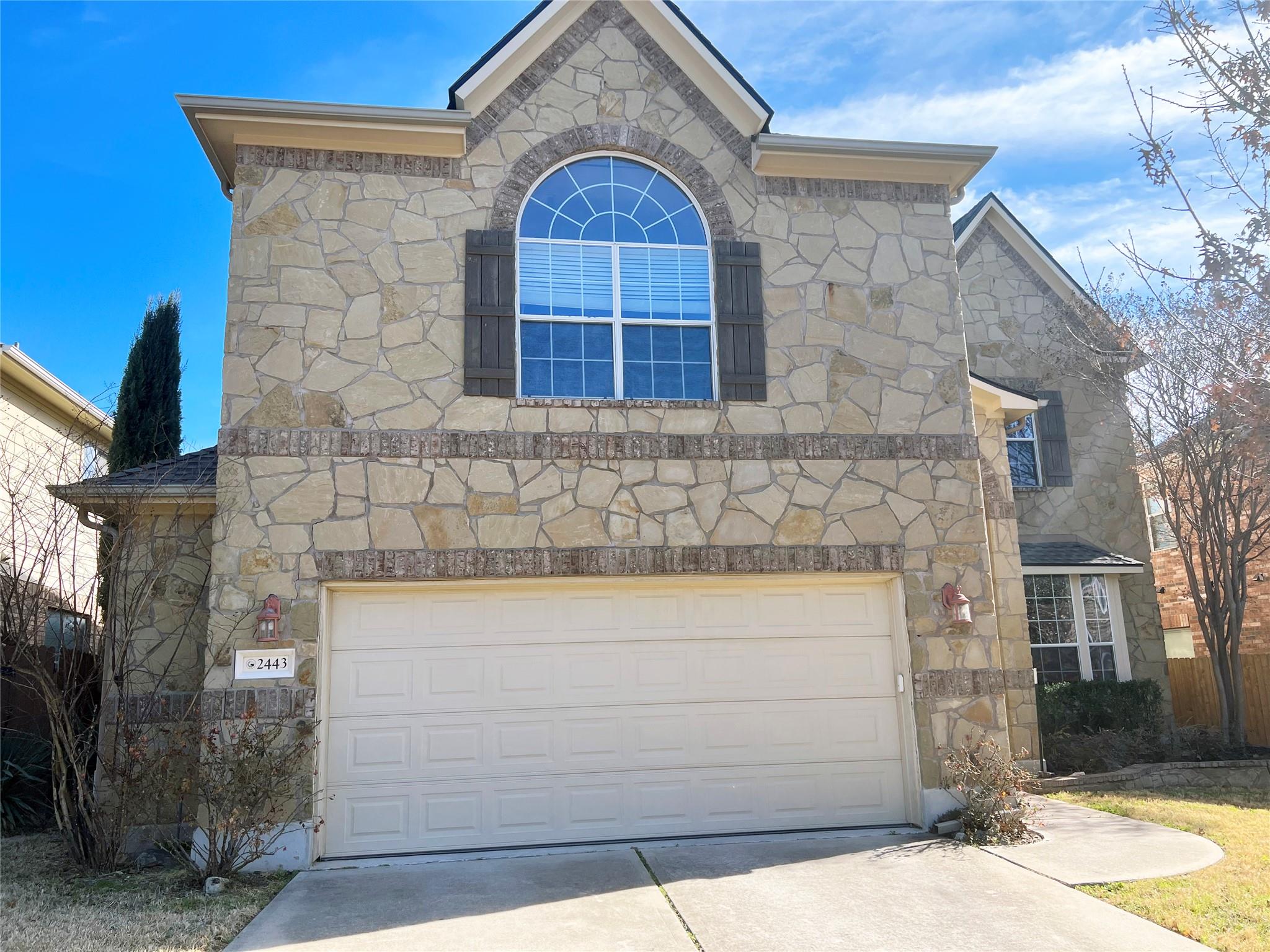 A stone-clad facade with an arched window and att
