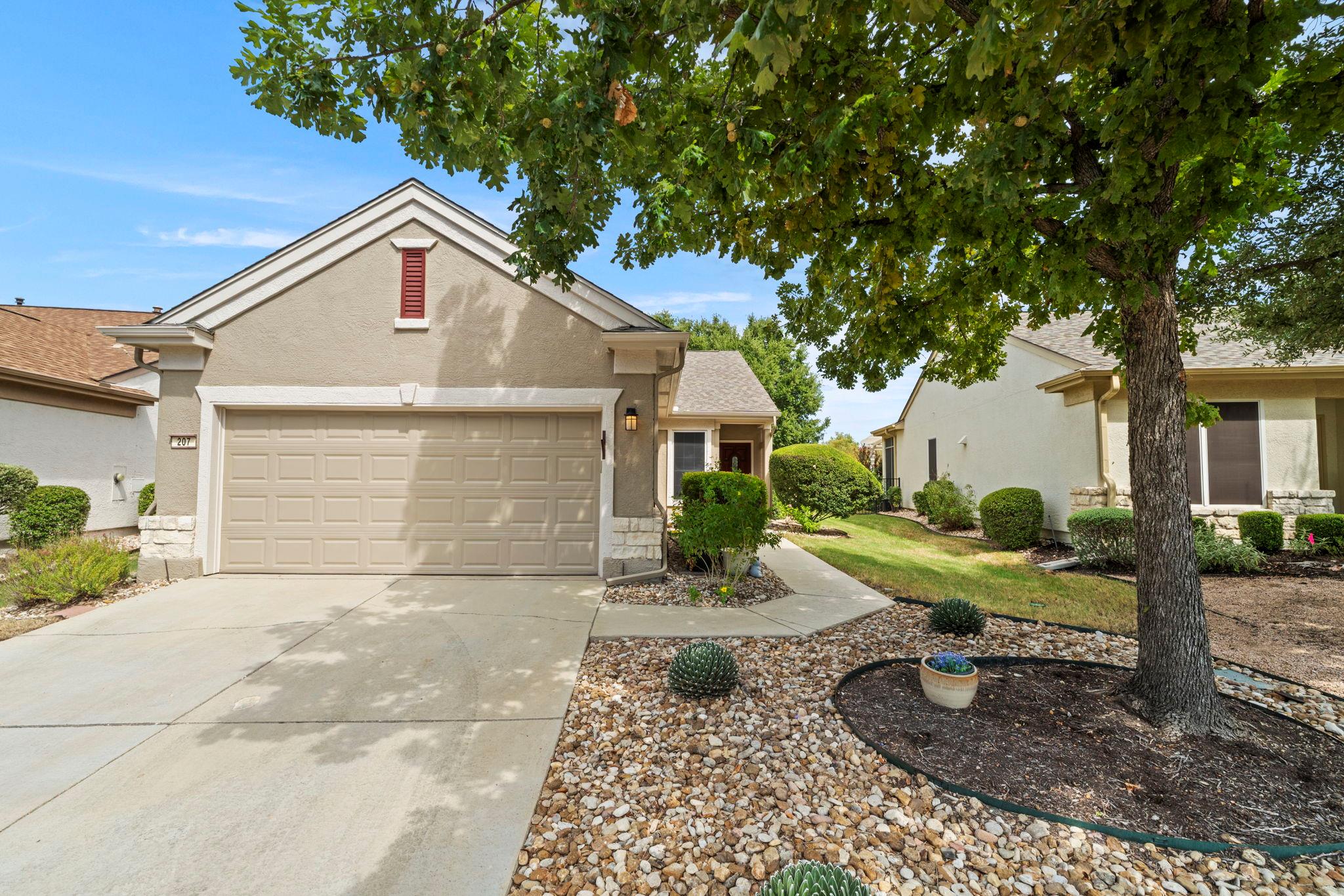 Manicured landscaping and a concrete driveway lea