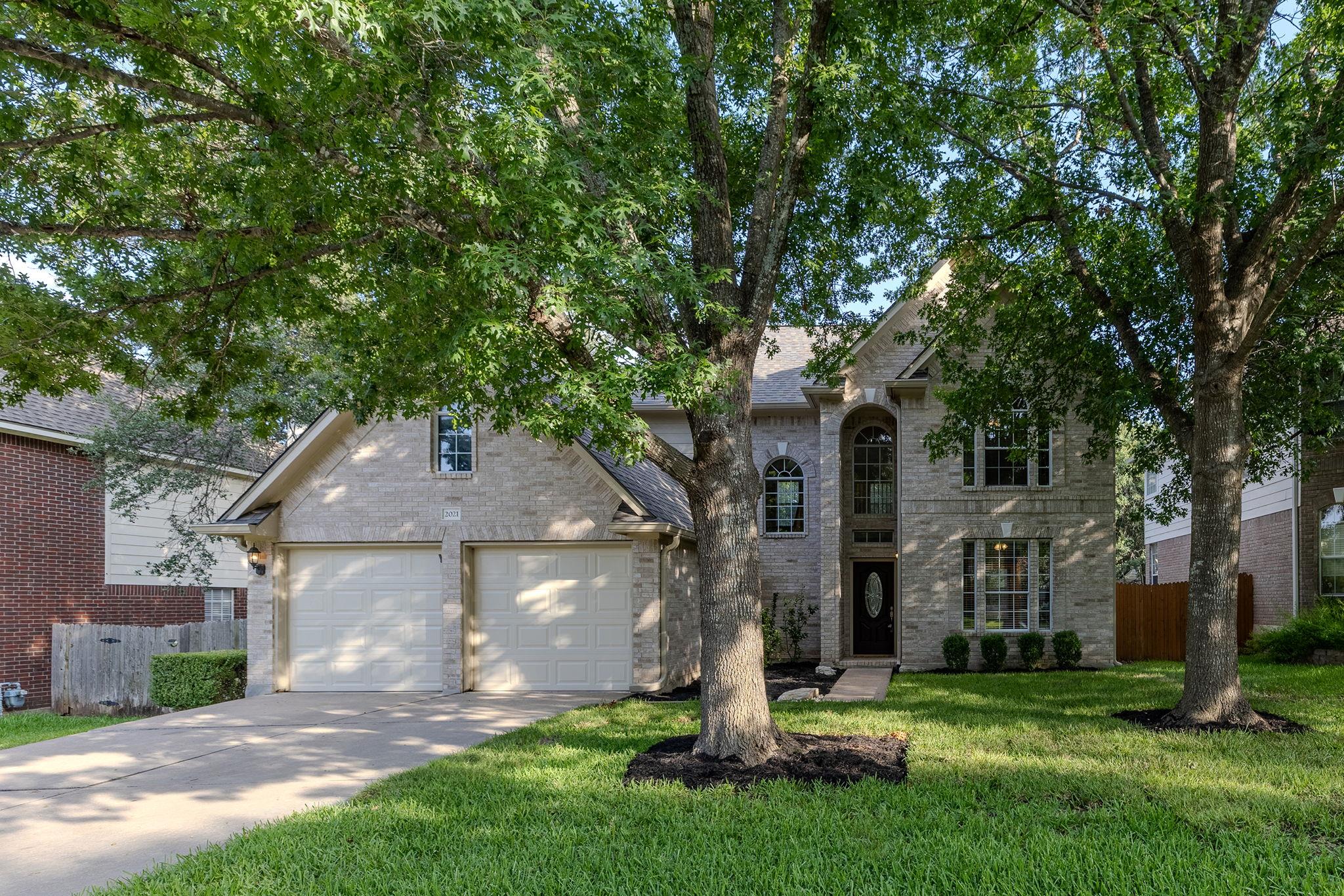 Mature trees shade the inviting brick facade of t