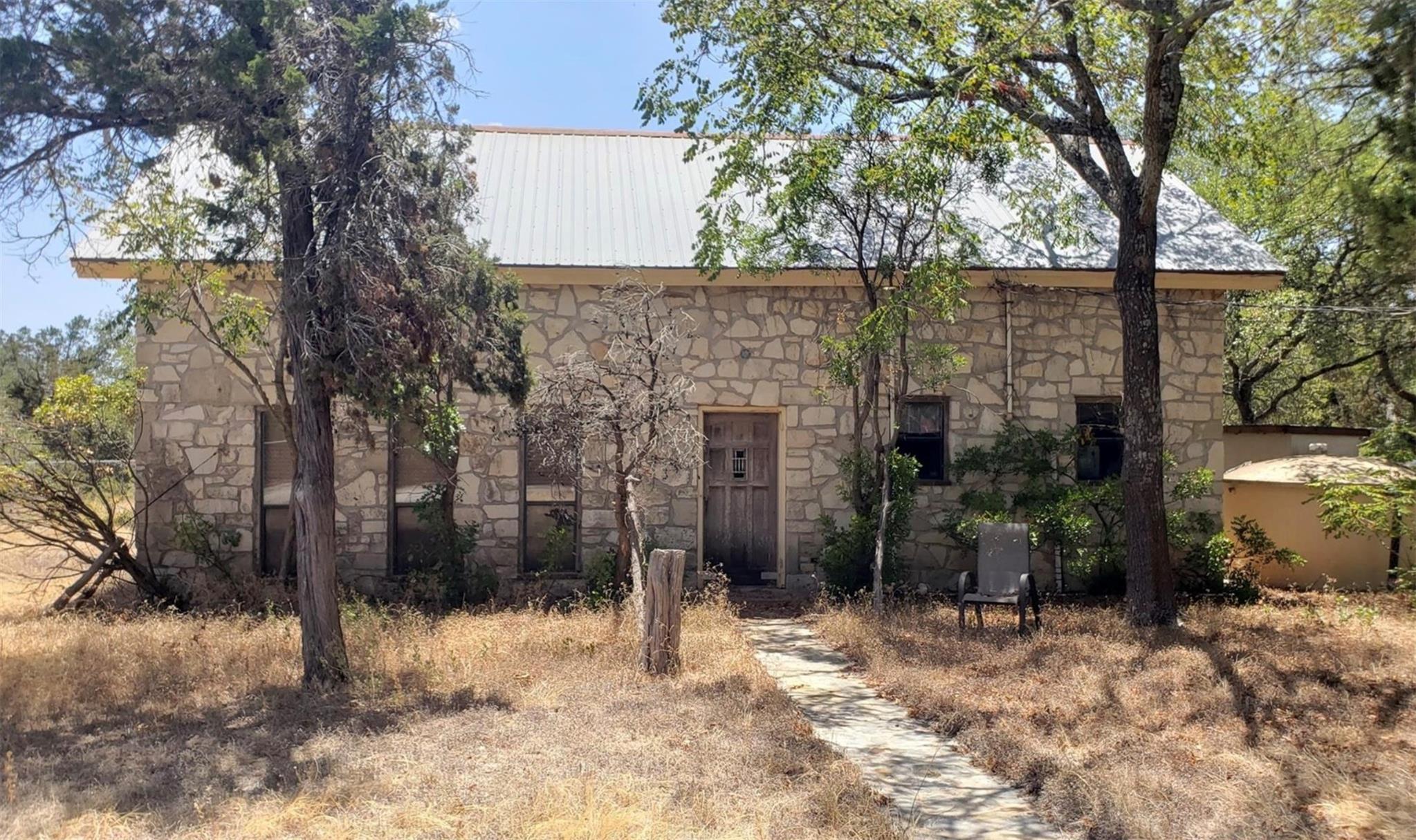 A rustic stone facade home, nestled amongst matur