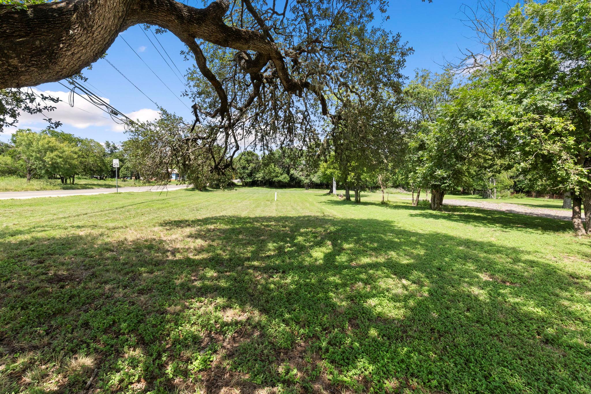 A spacious green lot awaits your vision, framed b