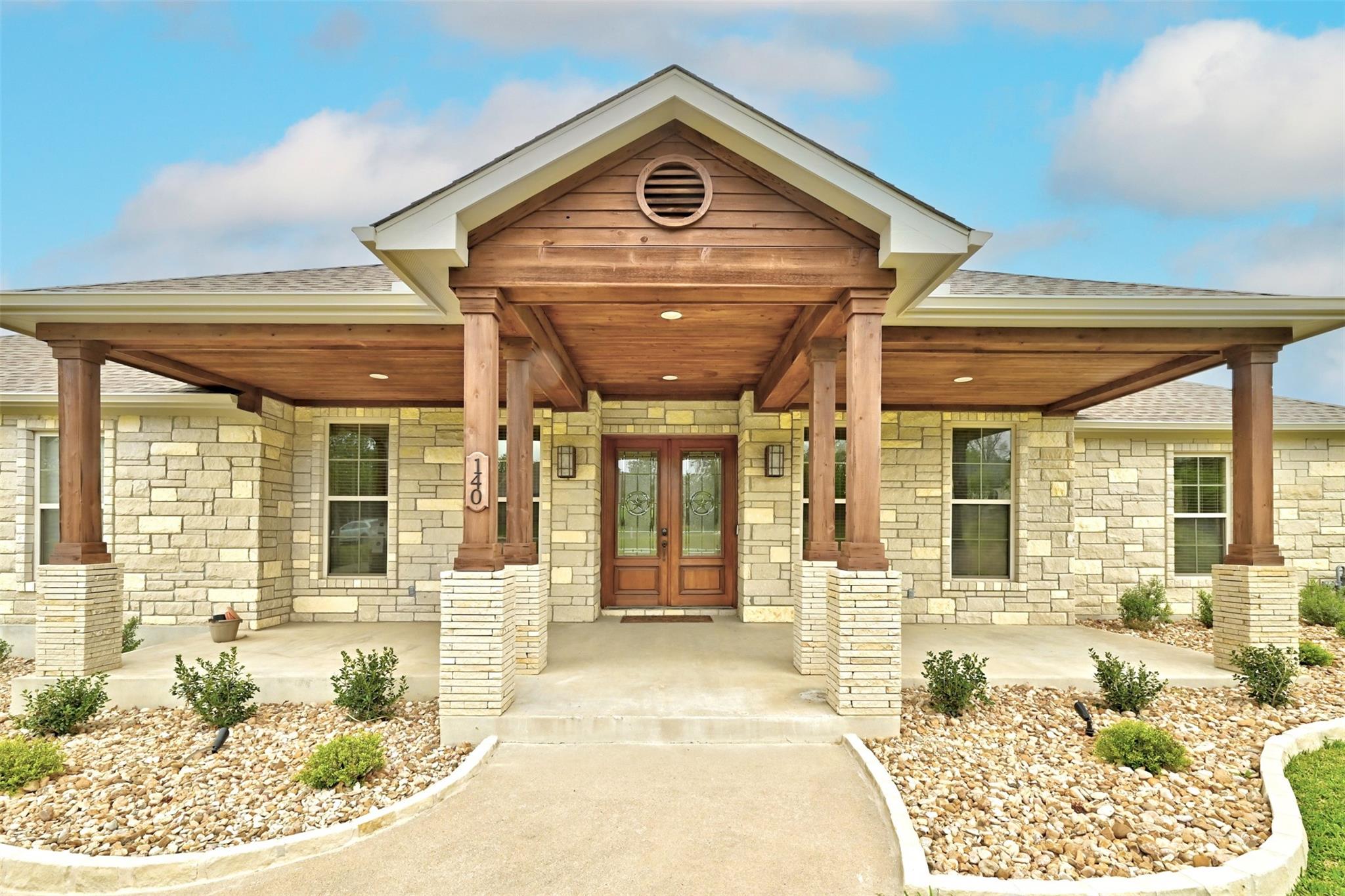 A welcoming stone facade with a covered wooden en