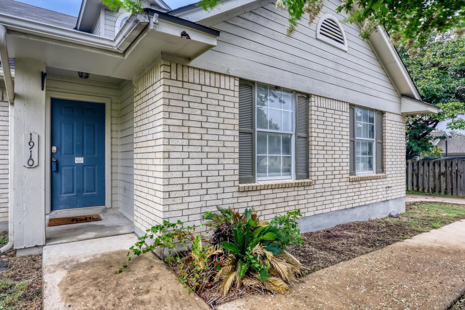 A welcoming blue door accents the brick and sidin