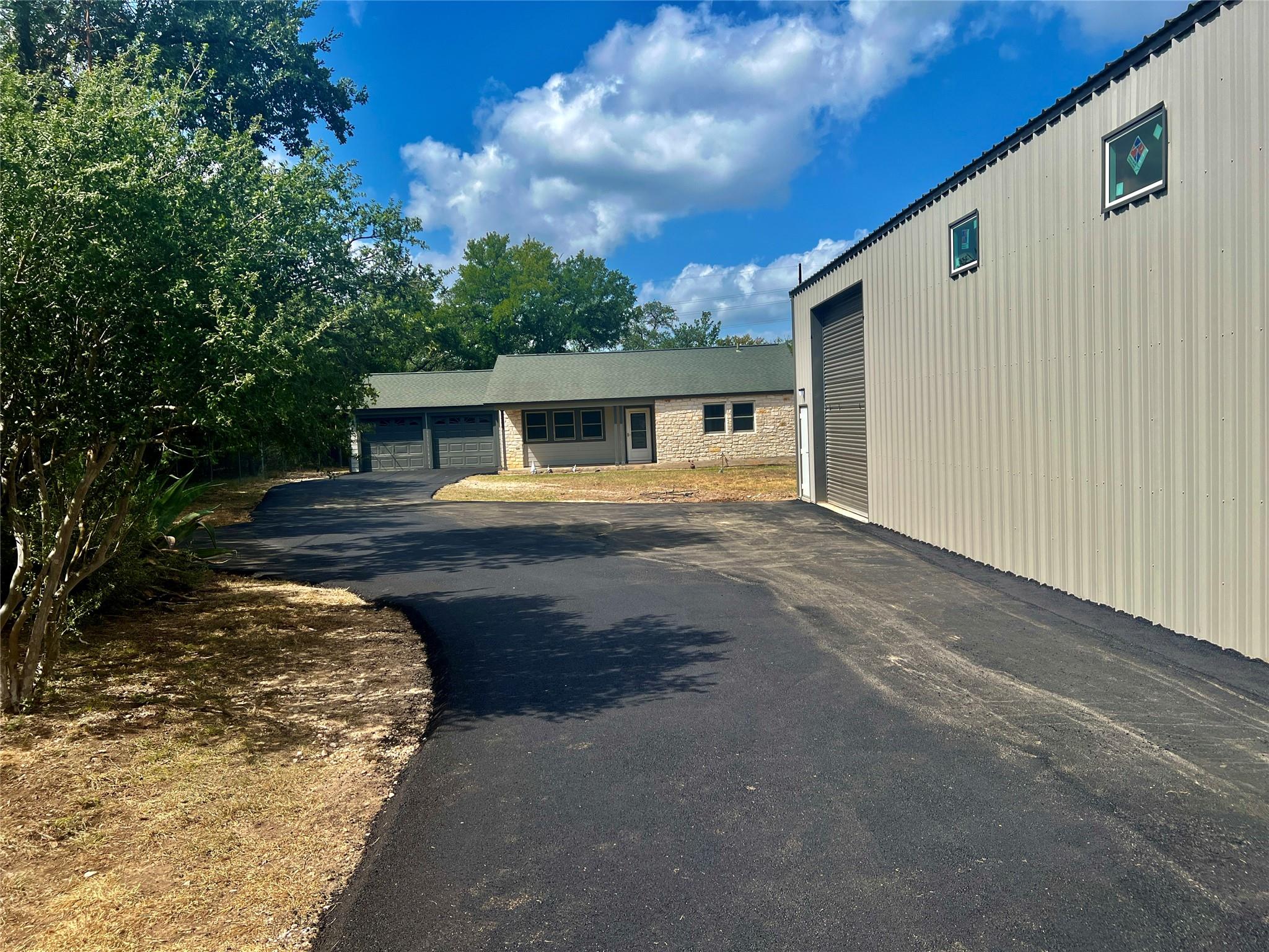 A long paved driveway leads past a large metal wo