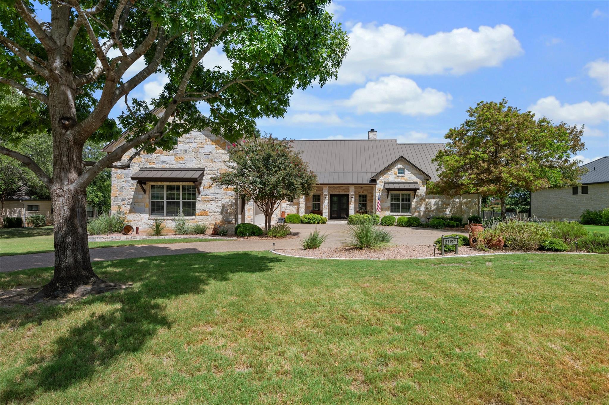 A grand stone facade home with a metal roof and w