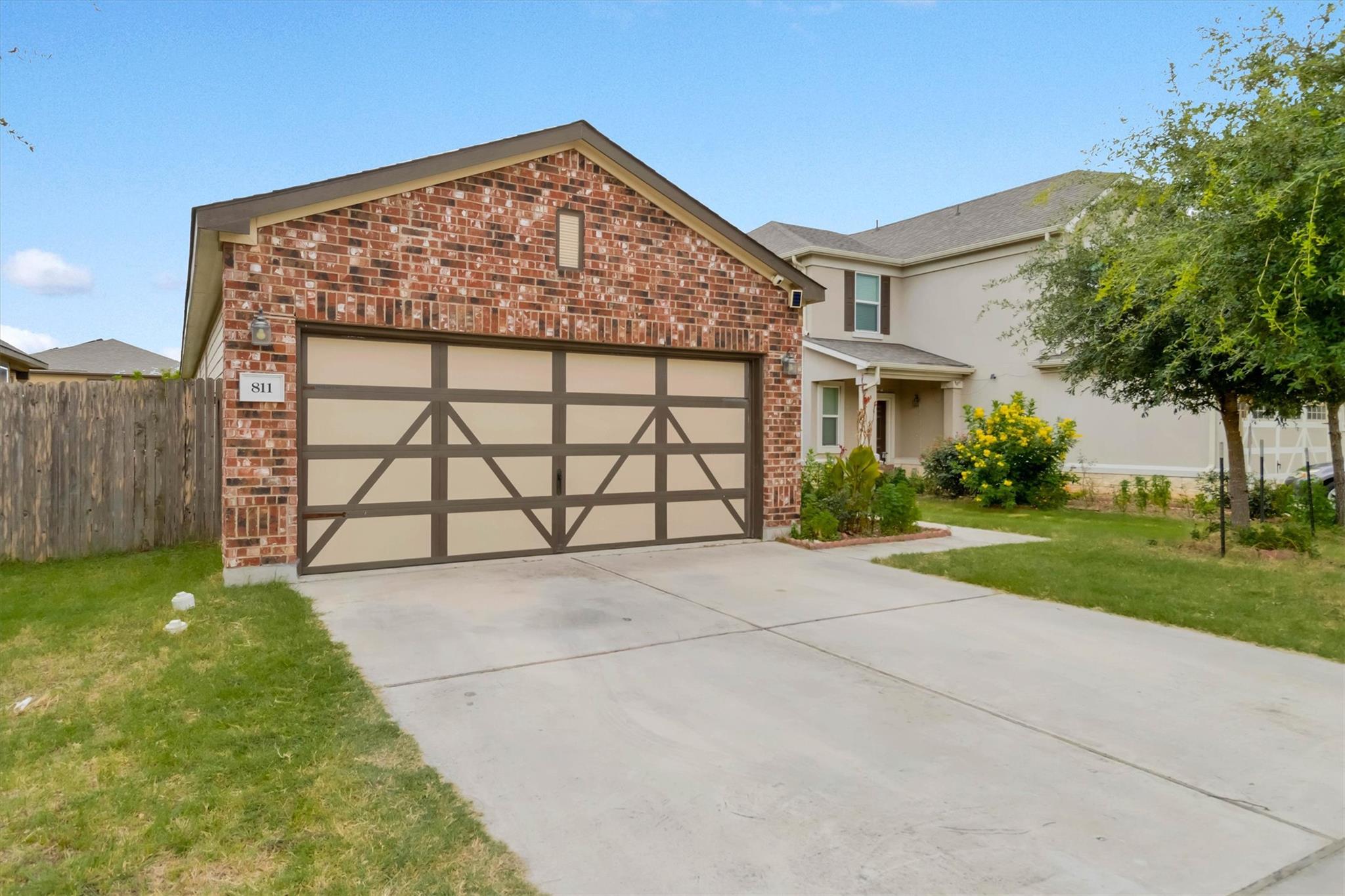 A well-kept driveway leads to a charming brick ga