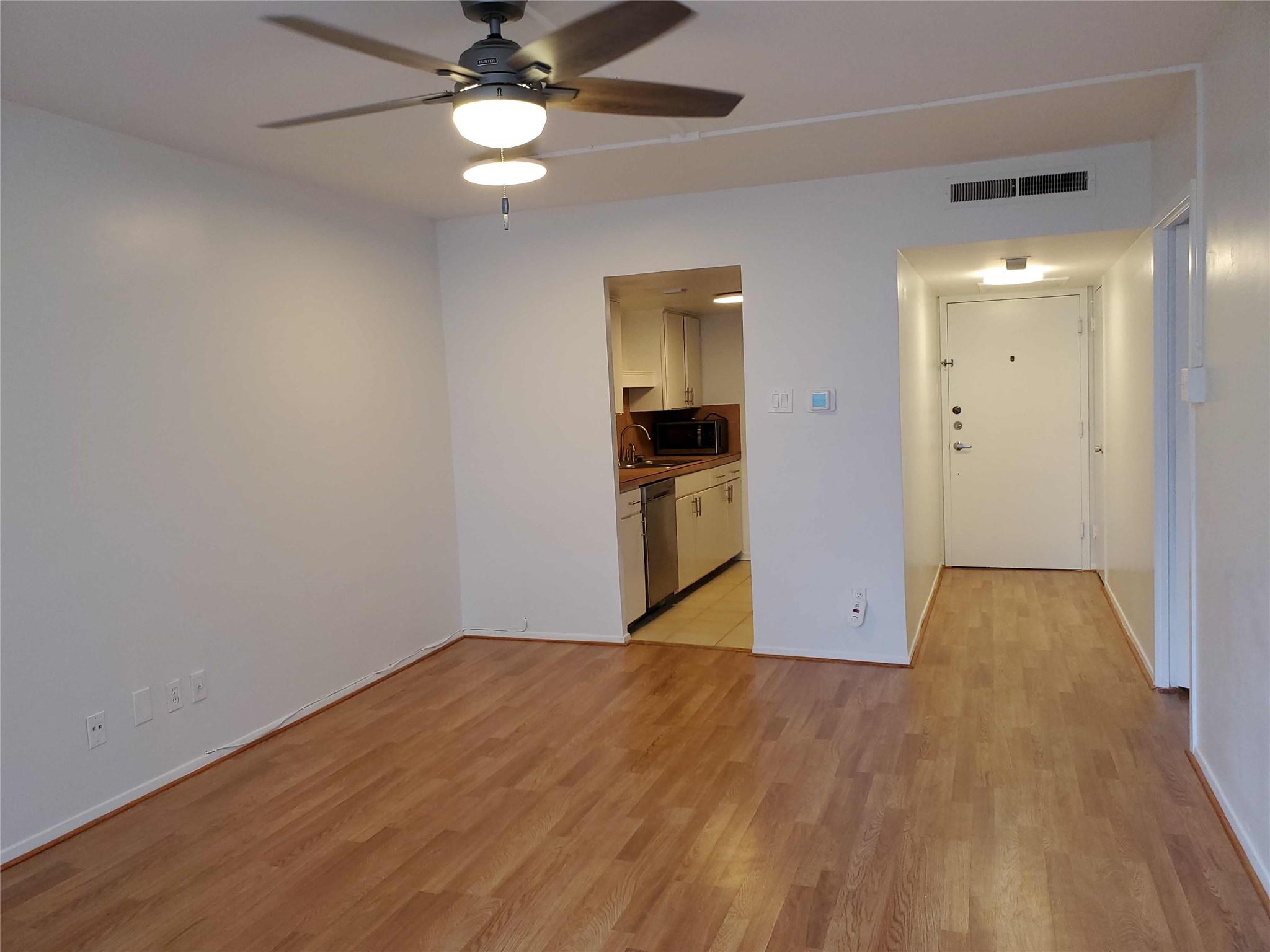 A living area with wood flooring flows into a wel