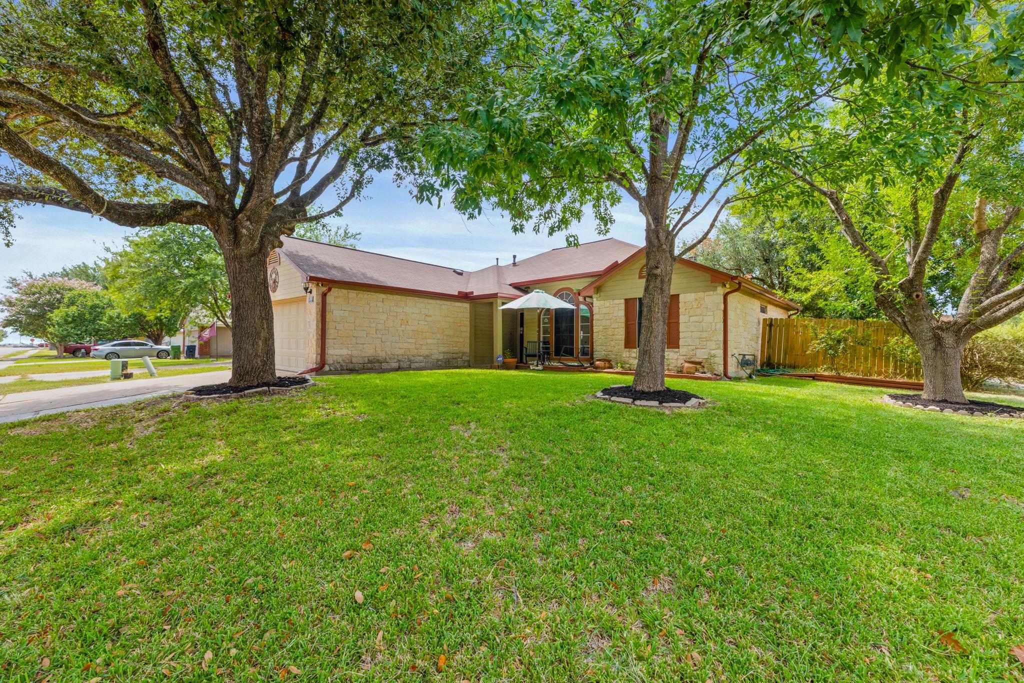 A well-maintained lawn with mature shade trees fr