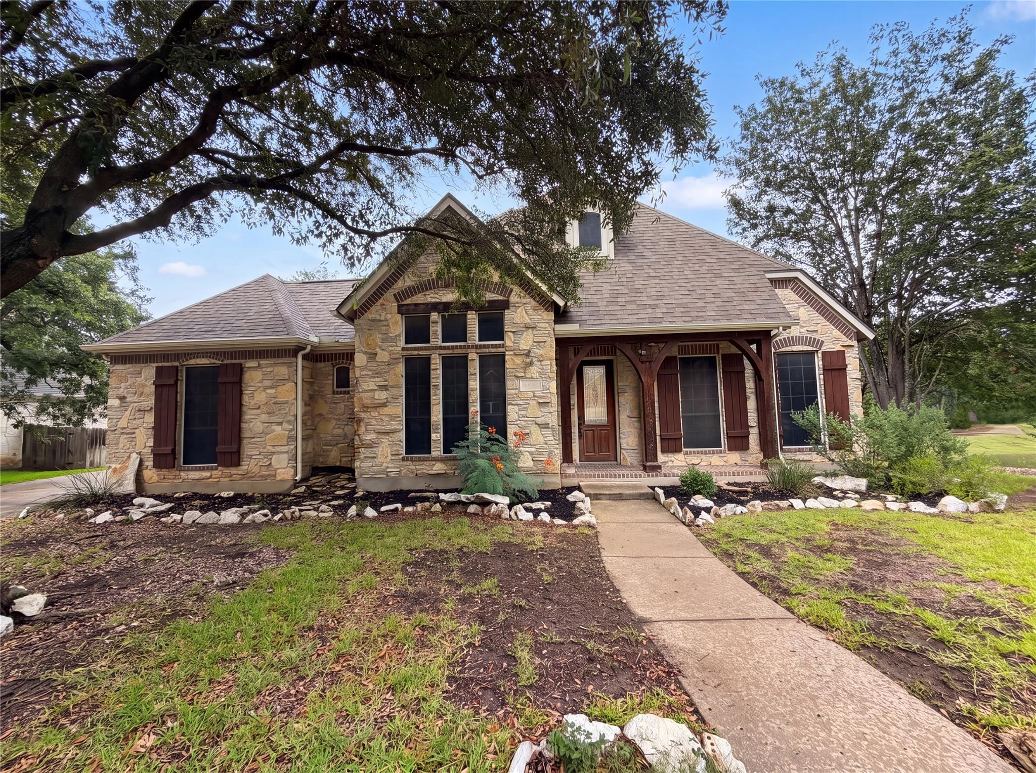 A stone-clad home welcomes with a covered entry a