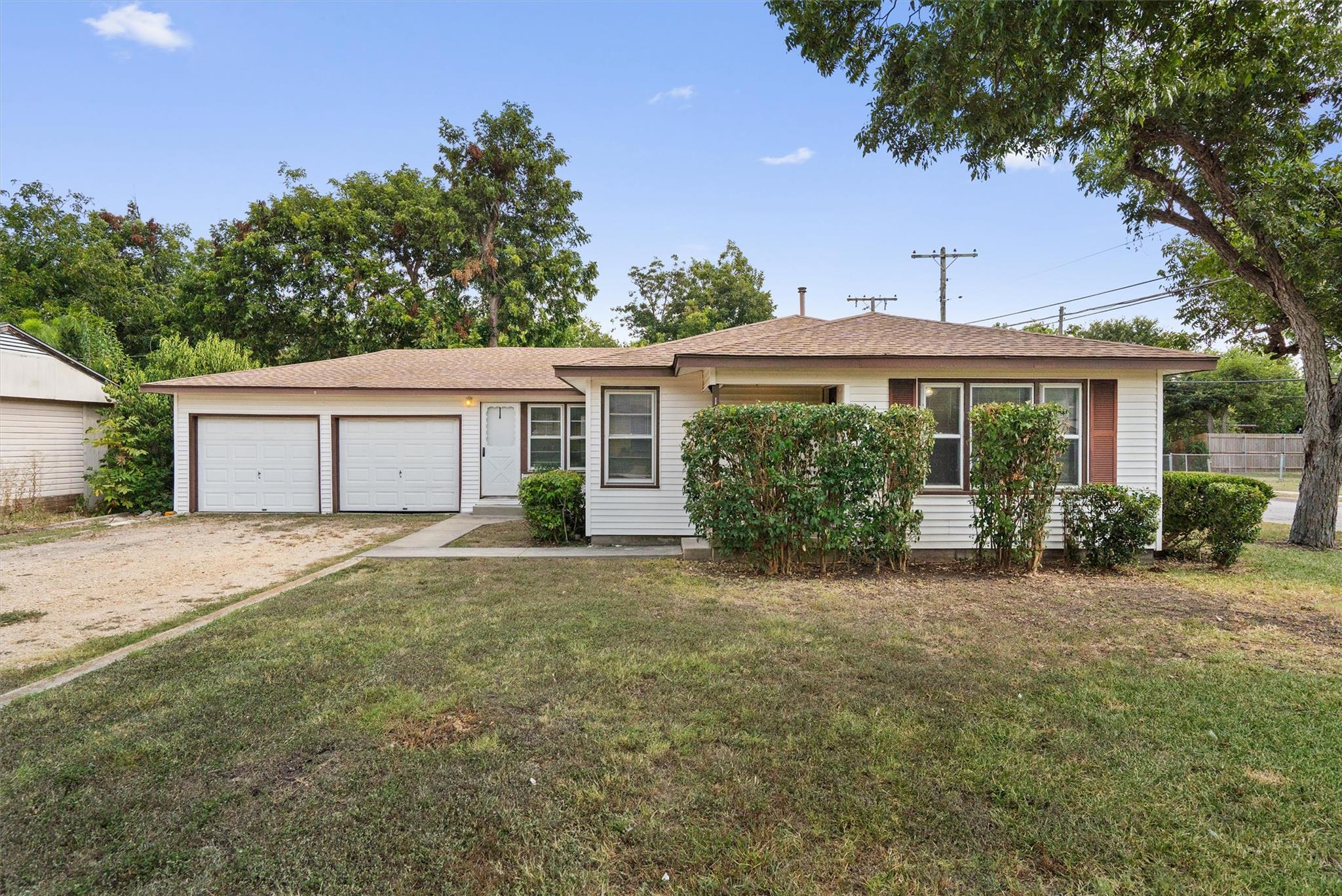 A classic ranch home features dual garage doors a