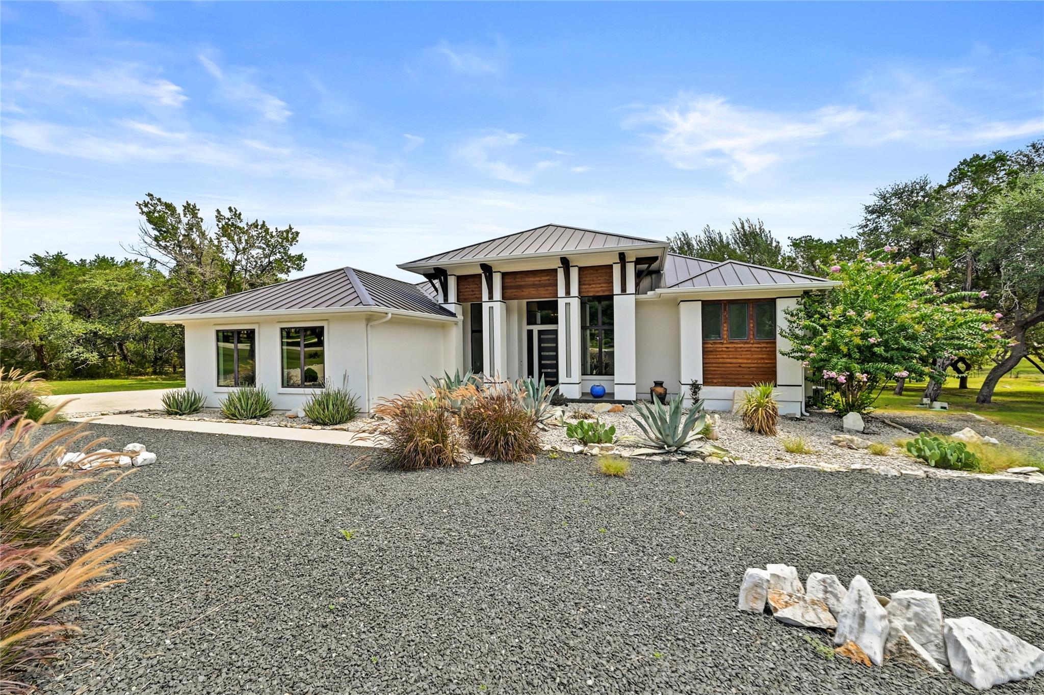 An inviting gravel driveway leads to this modern 