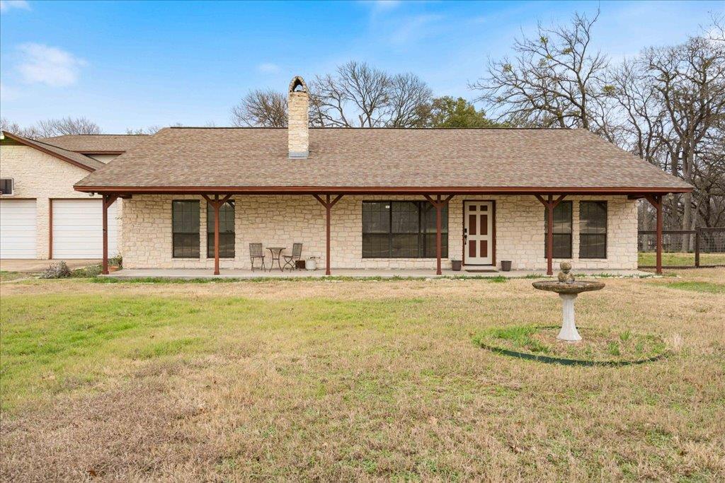 A welcoming stone-clad ranch home boasts a covere