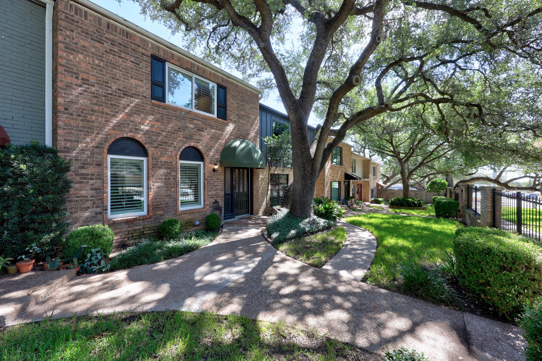 Mature oak trees shade a curved pathway leading t
