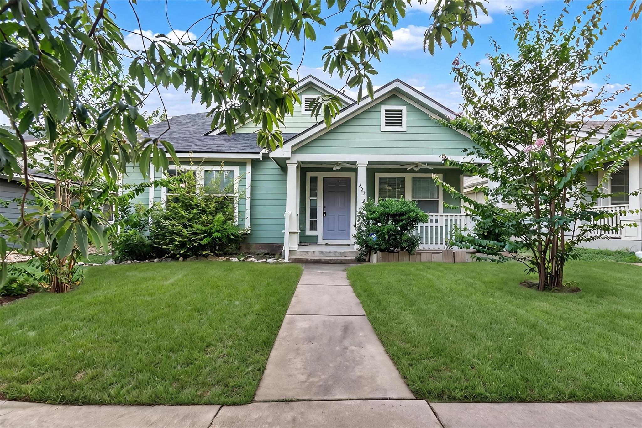 A charming sage green home with a welcoming front