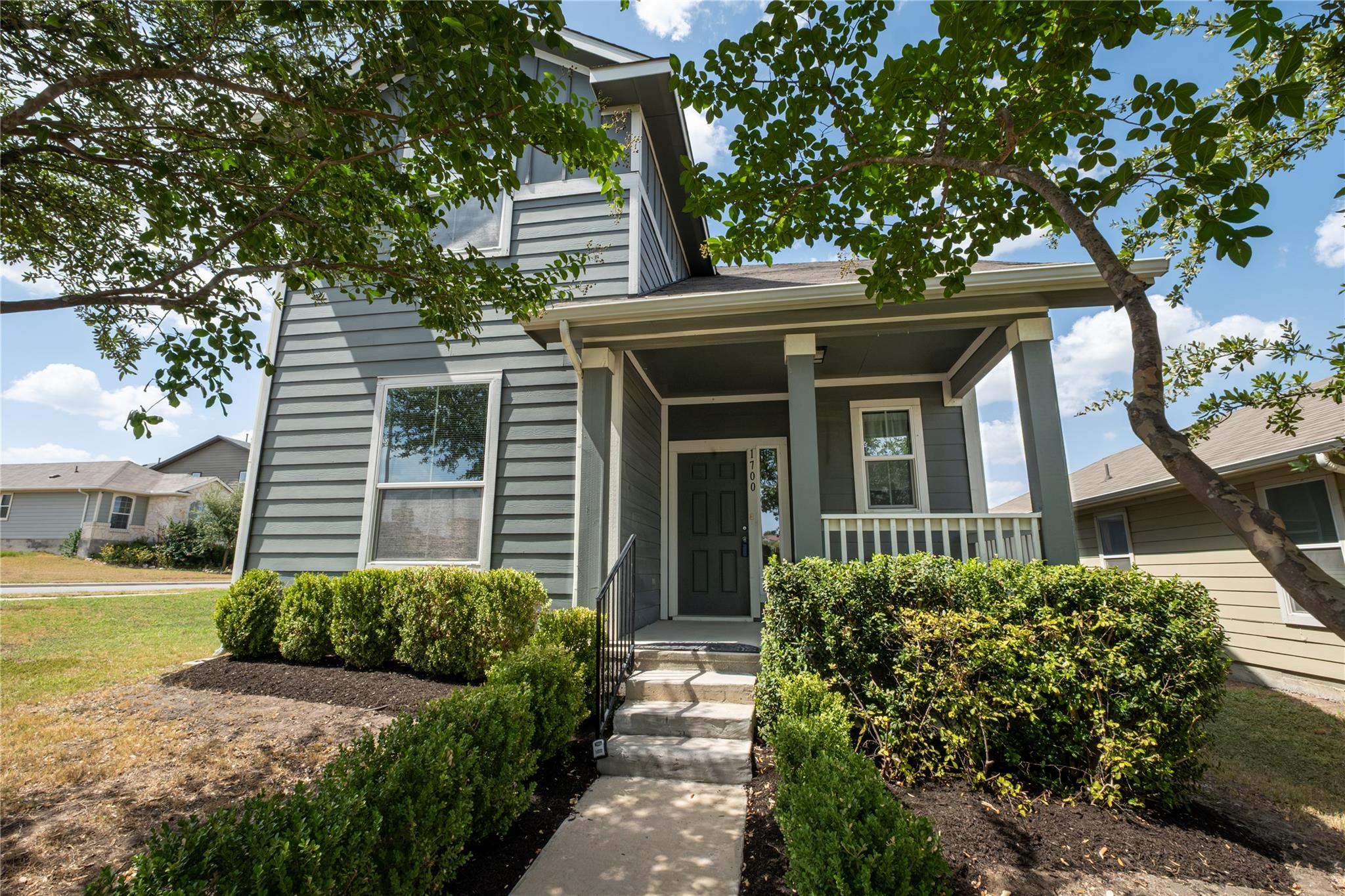 Mature trees shade a welcoming front porch and la