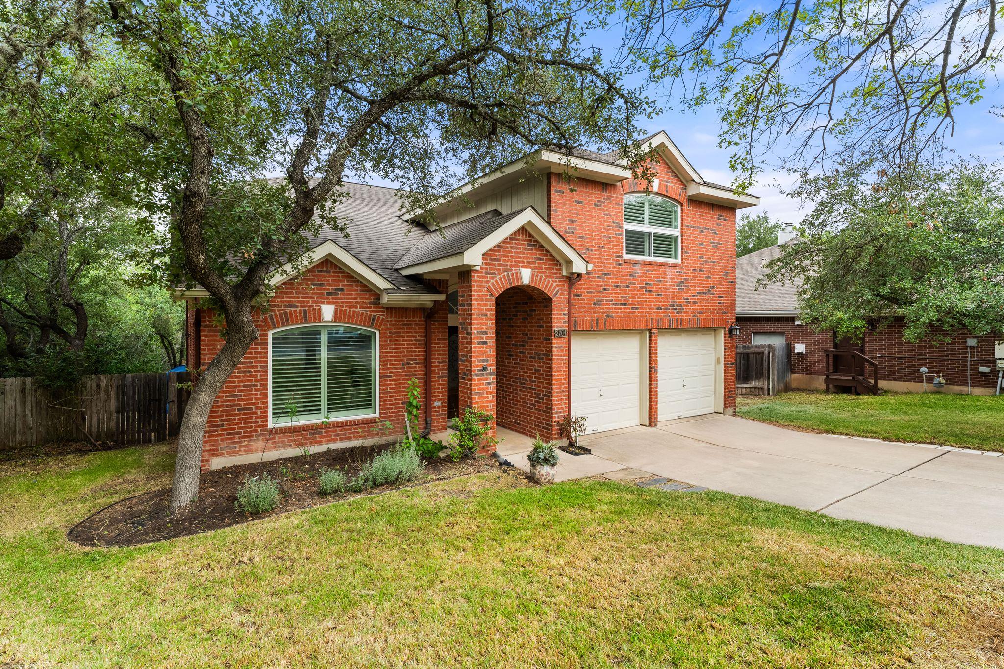 Brick facade home offers two-car garage and matur