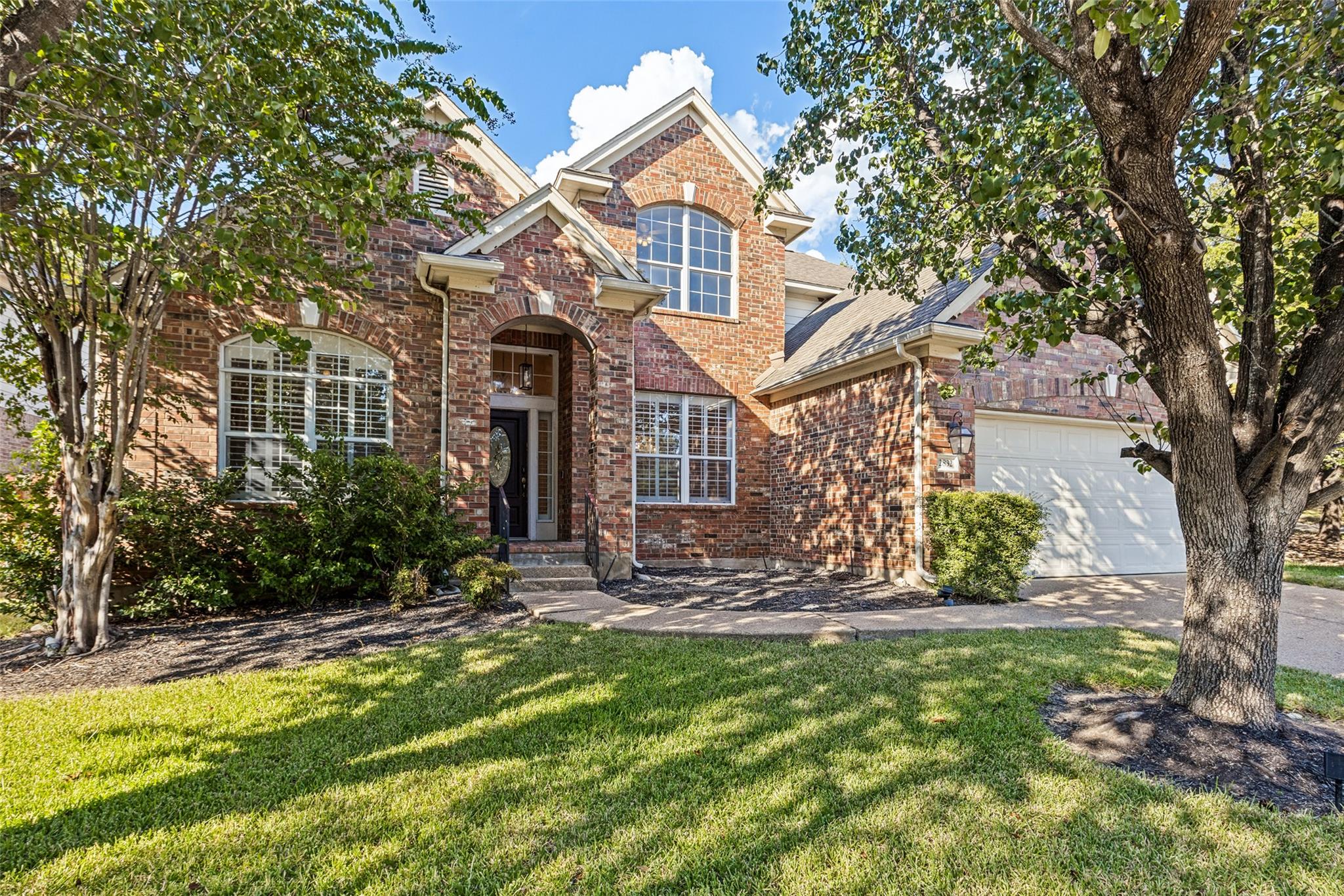 Mature trees frame a classic brick exterior with 