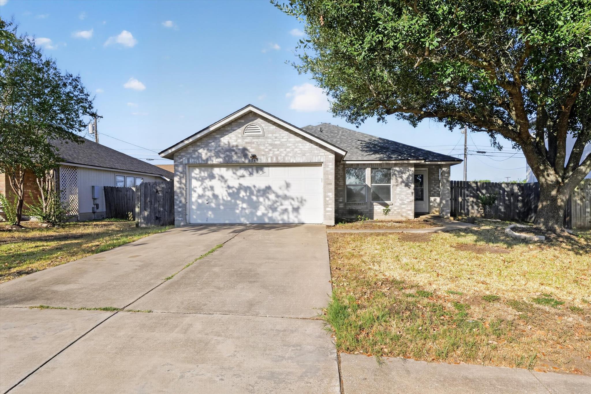 Mature trees shade the front lawn of this brick h