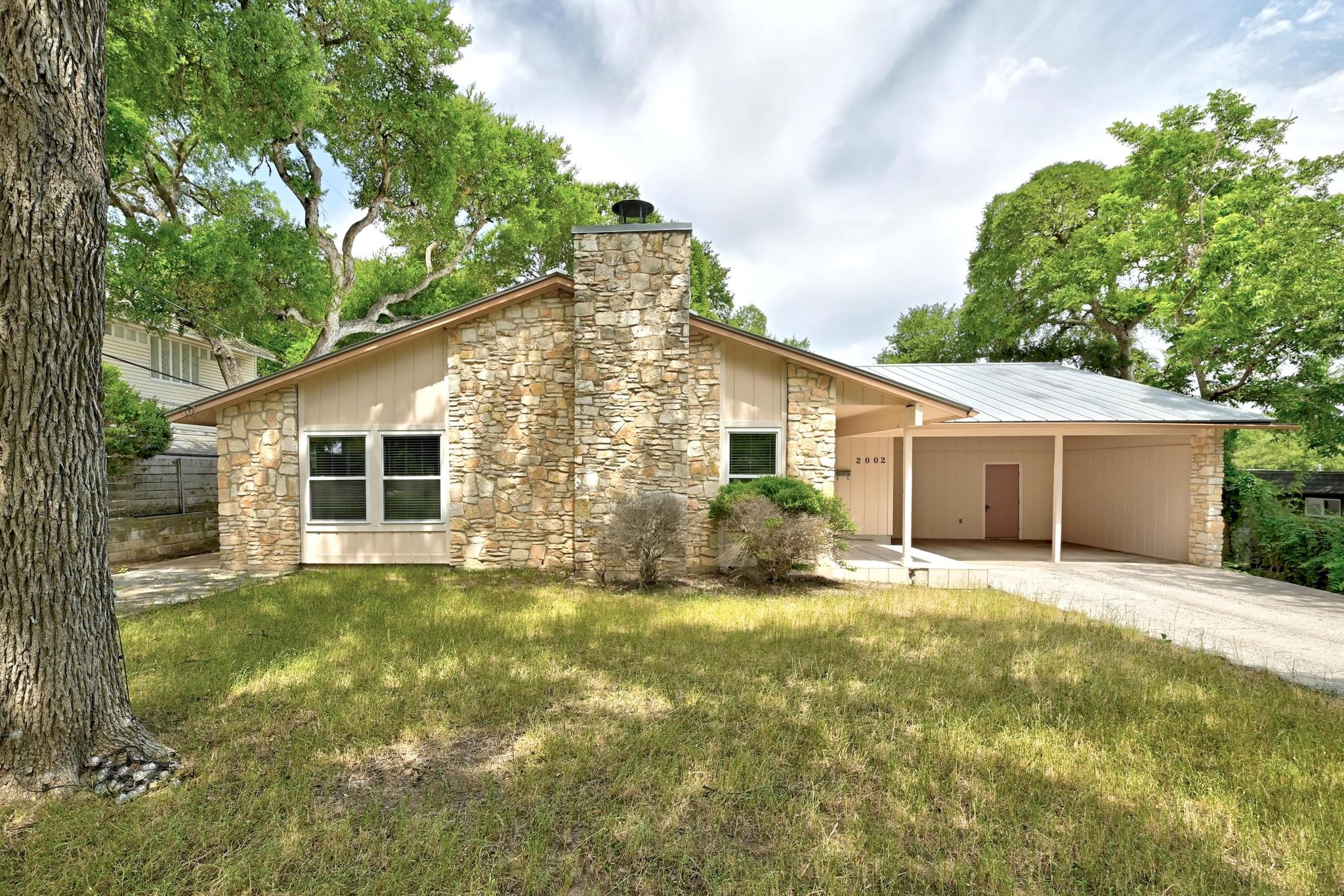 A striking stone facade and carport create a welc