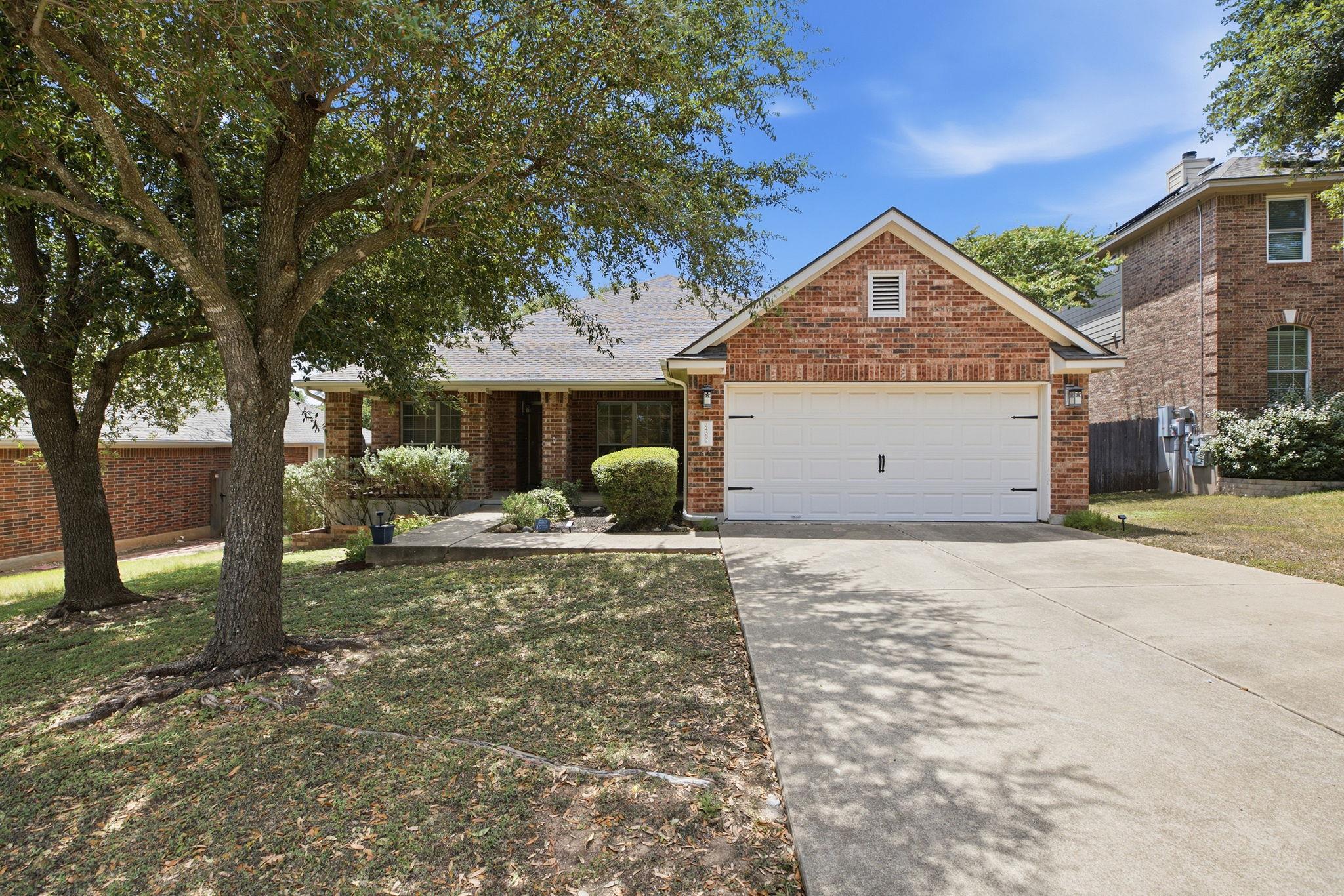 Established trees shade the concrete driveway and