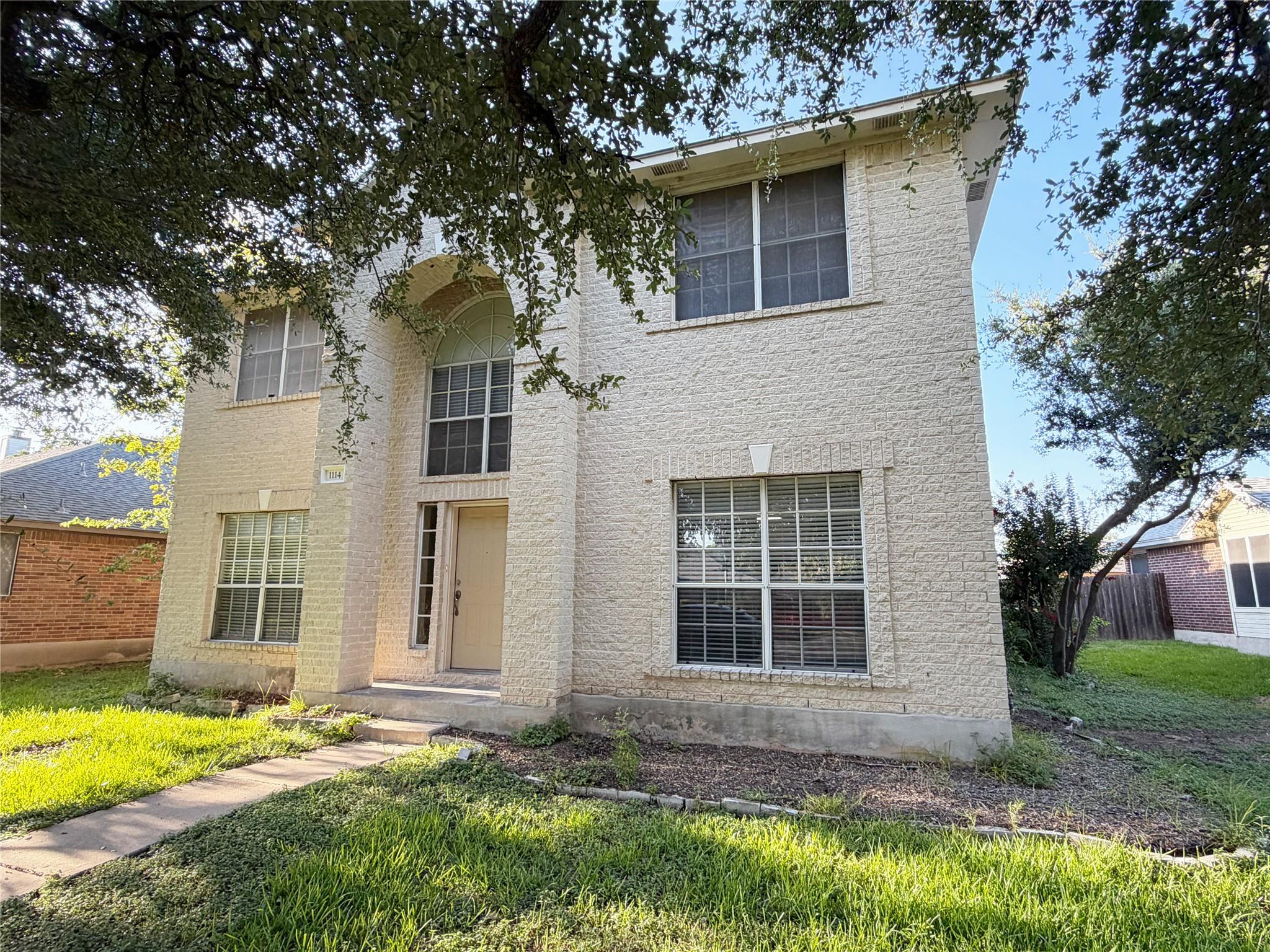 A cream-colored brick facade welcomes with a tall