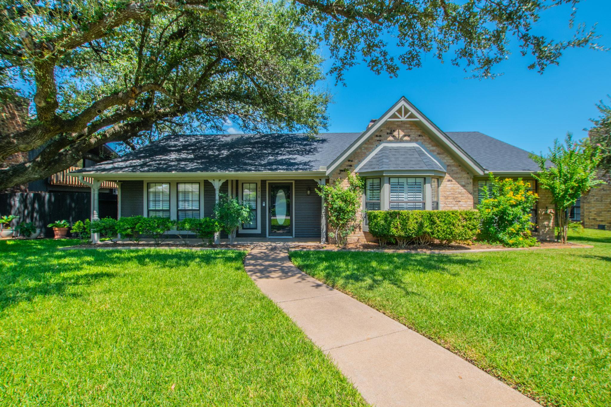 A well-maintained lawn and mature tree embrace th