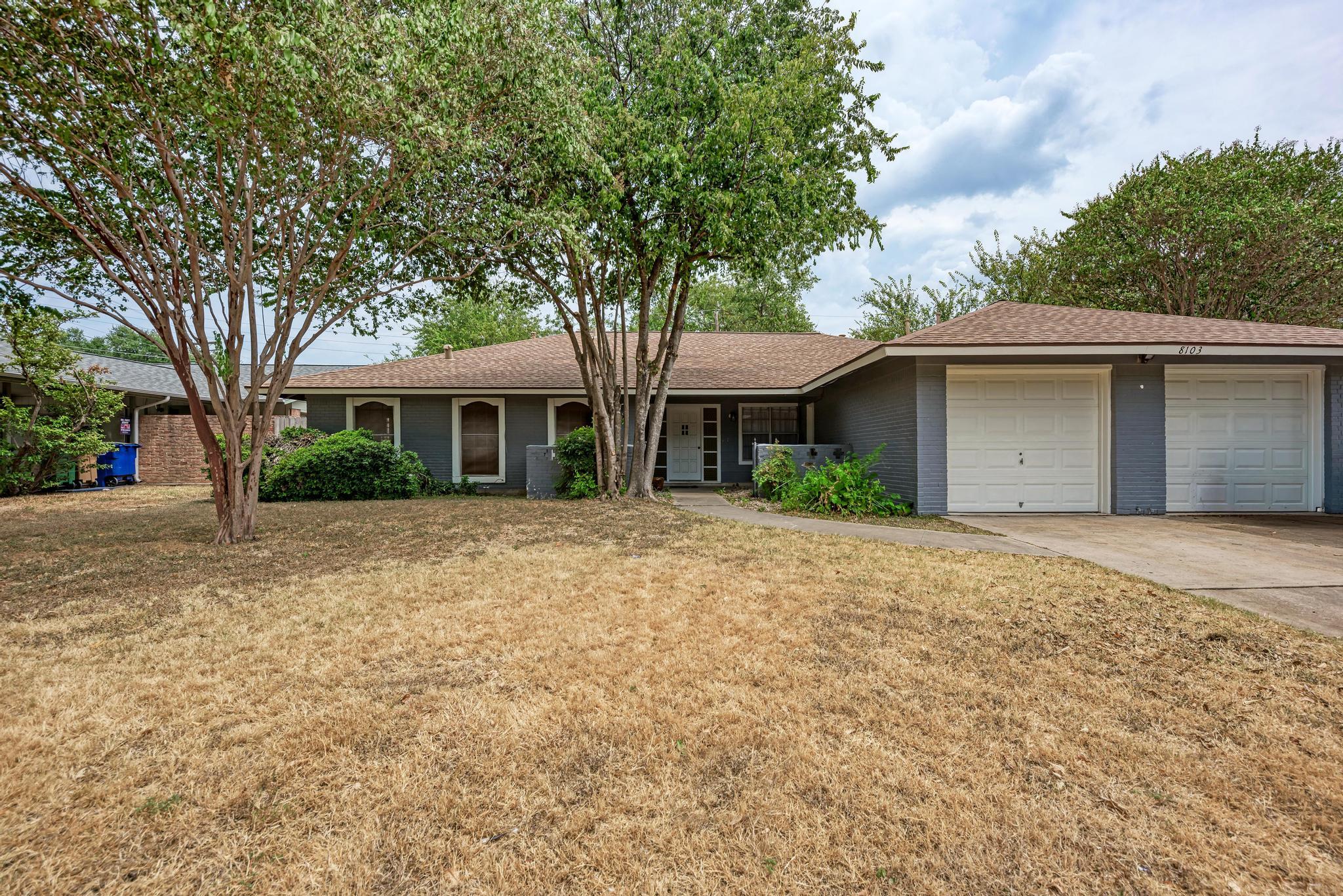 Mature trees frame the front yard and classic fac