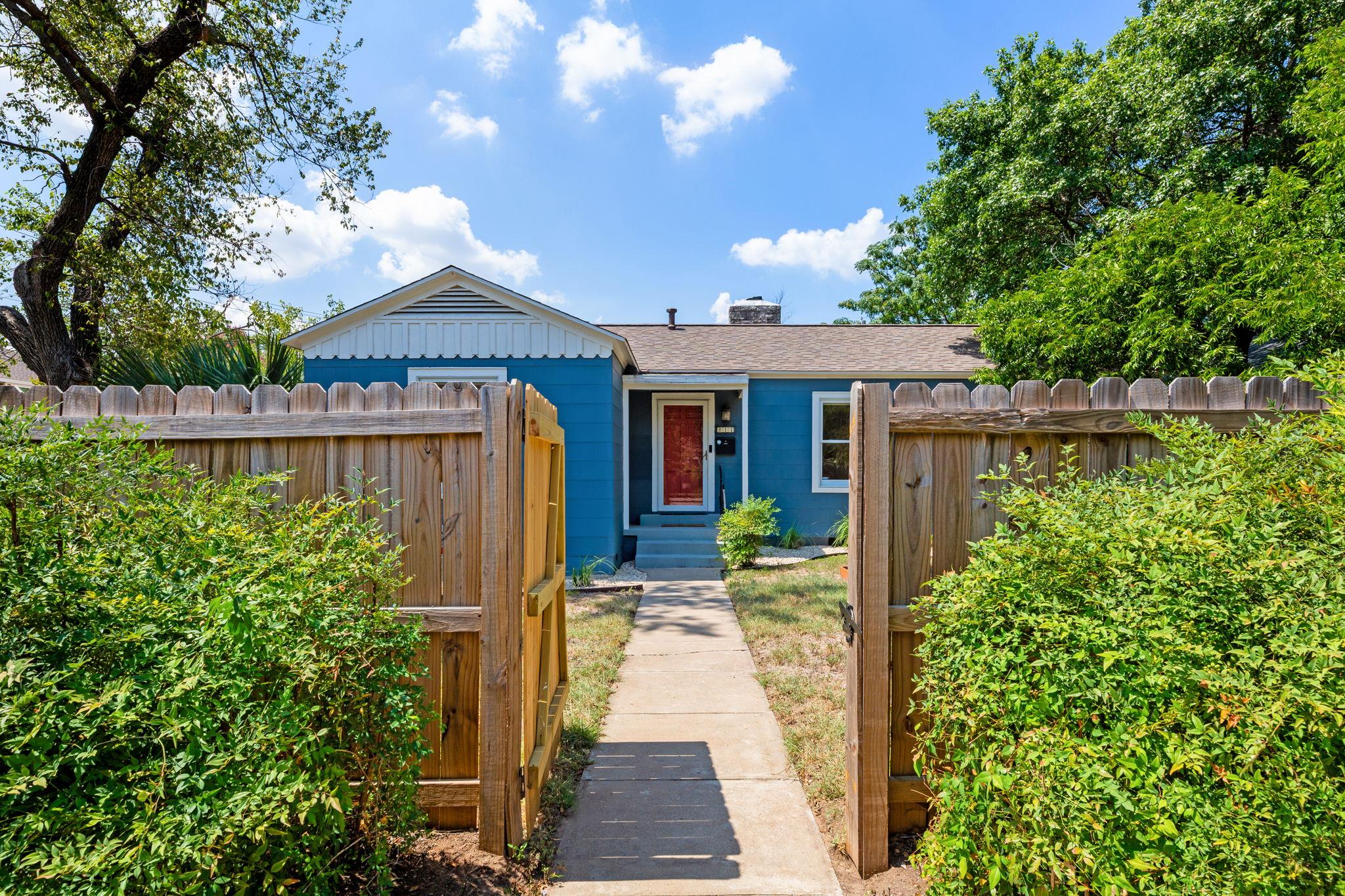 A charming blue residence awaits behind a welcomi