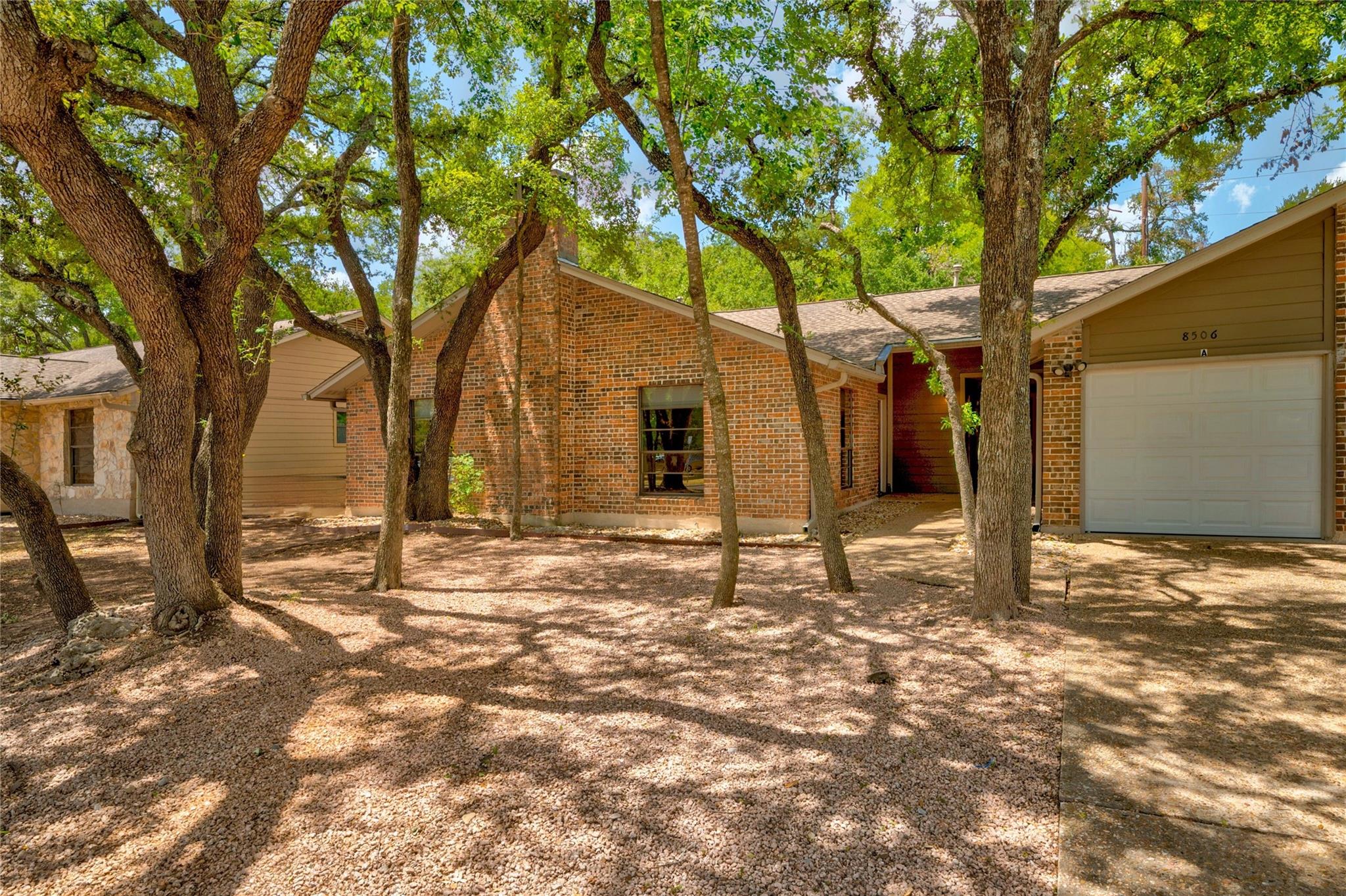 Mature trees shade a charming brick home with an 