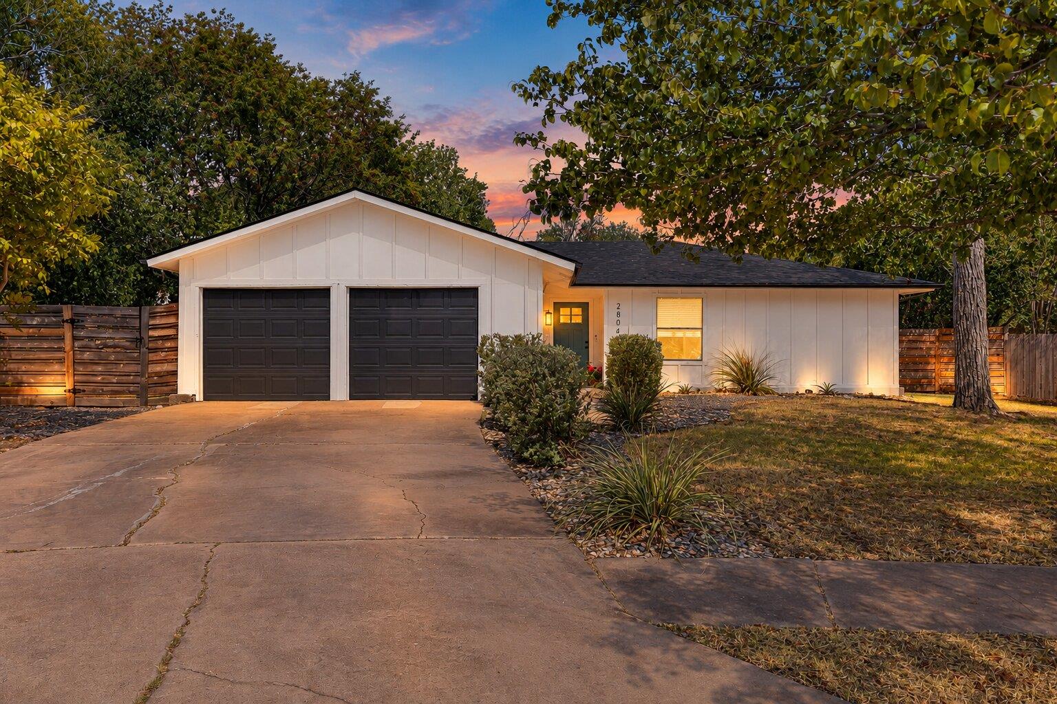 Mature trees frame a welcoming single-story exter