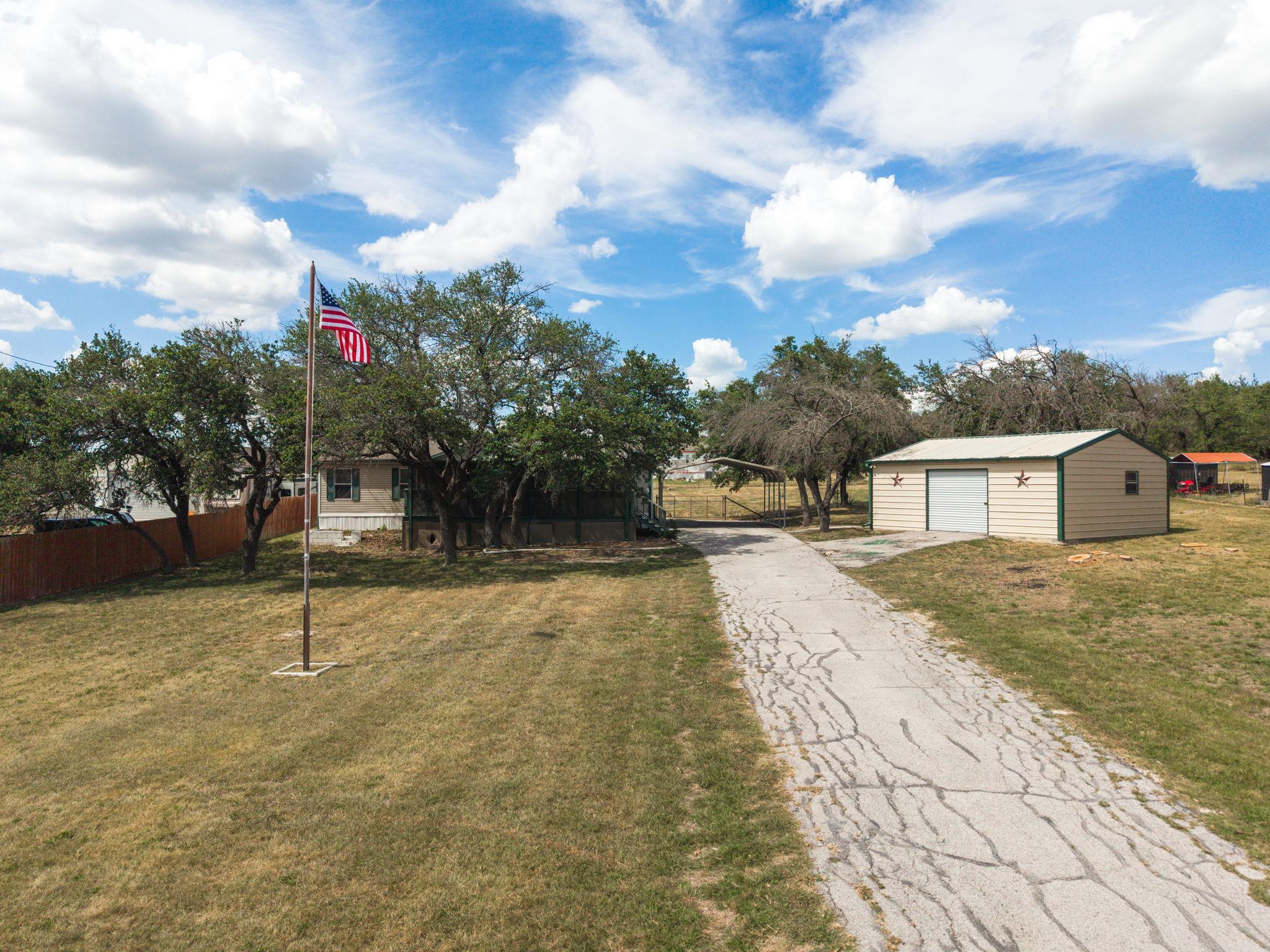 A long paved driveway leads to a modest home with