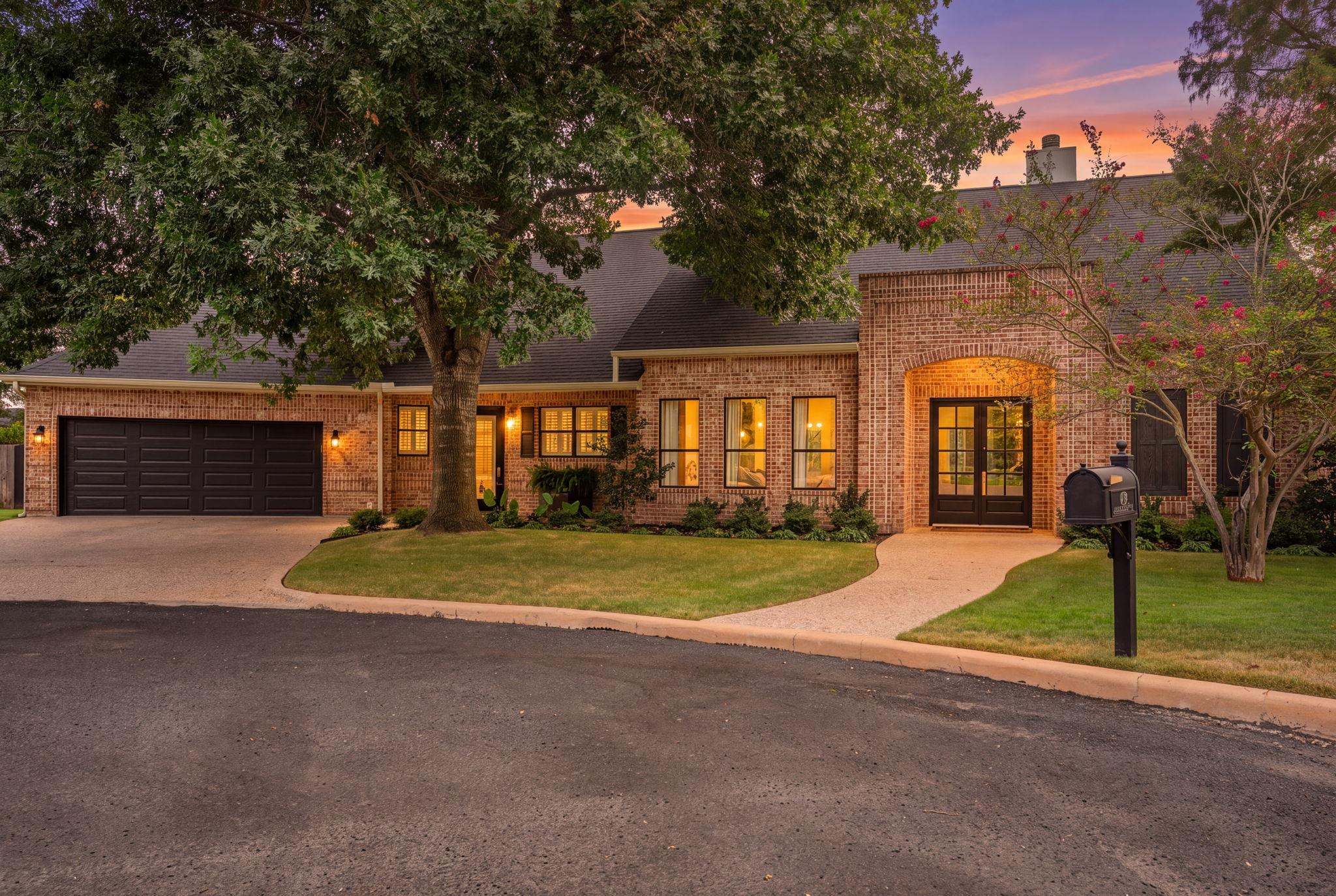 A classic brick exterior stands framed by mature 