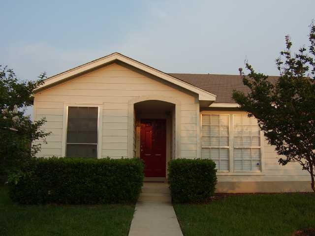 A welcoming red entry door with neatly trimmed he
