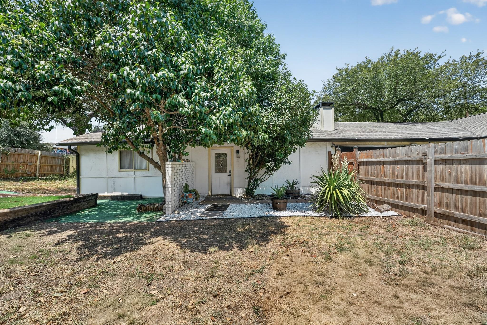 Mature trees shade a private rear entry flanked b