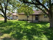 Mature trees shade a welcoming residence with a d