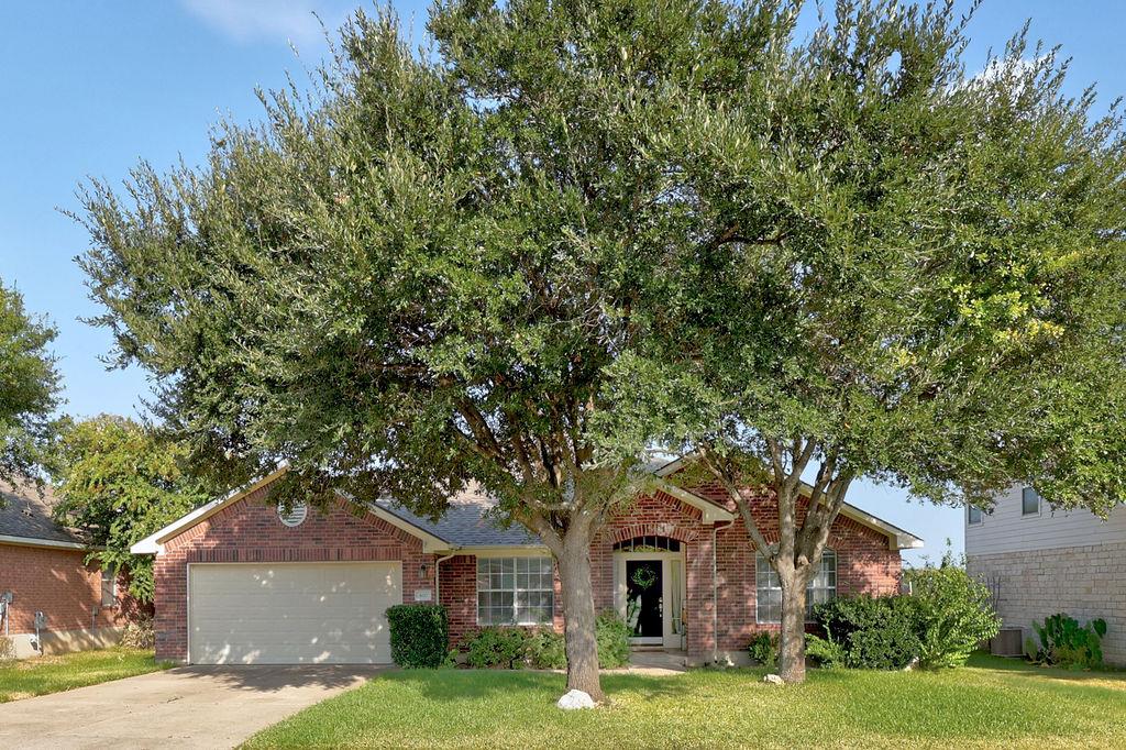 Mature trees shade a classic brick exterior featu