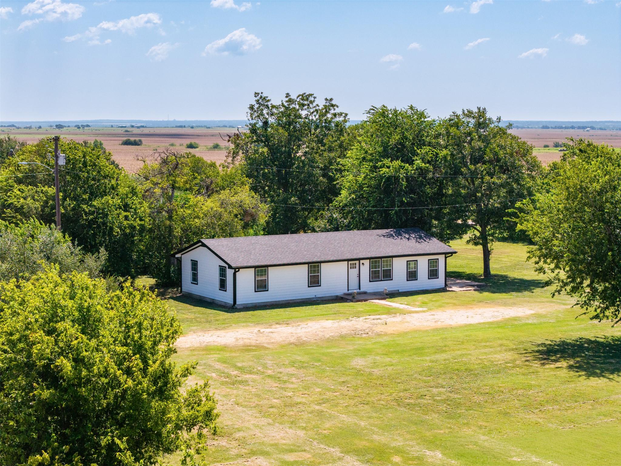 A single-story country home sits surrounded by ma