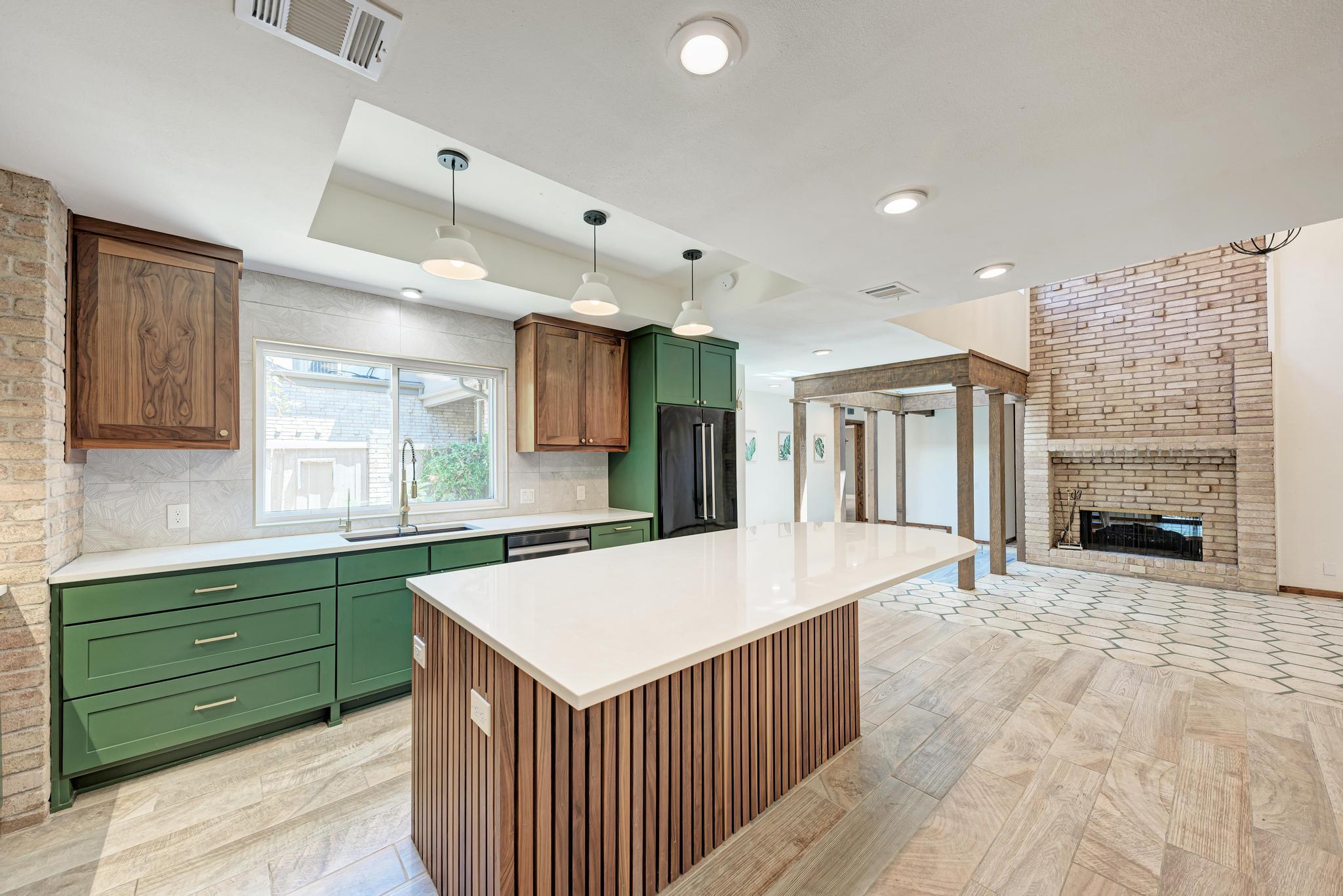 An open kitchen layout features custom green cabi