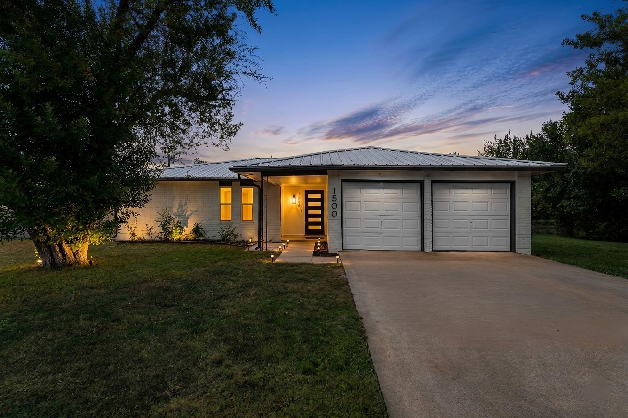 Lush landscaping and two garage doors greet guest